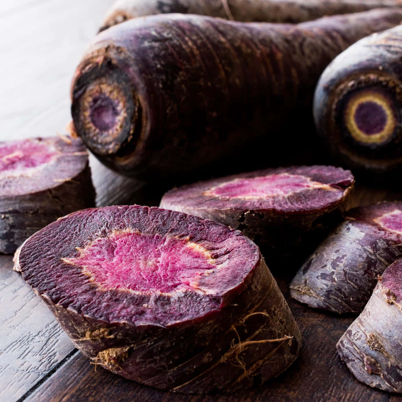 Purple Carrots 桌布 壁紙 — 切片紫色胡蘿蔔在質樸的木質表面上展現出充滿活力的洋紅色內部。