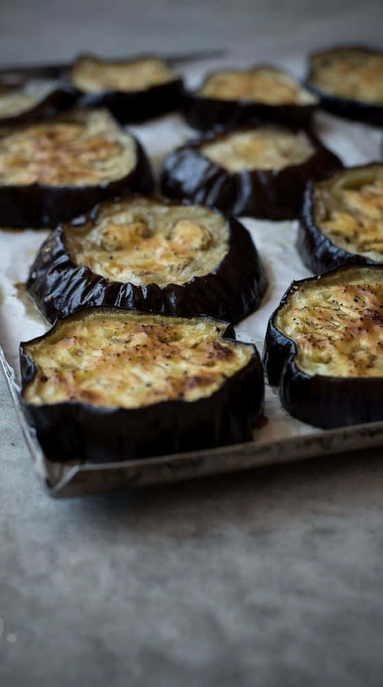 Black Garlic 桌布 壁紙 — 切片茄子填入金黃色起司餡料烤製，放在鋪有烘焙紙的烤盤上。