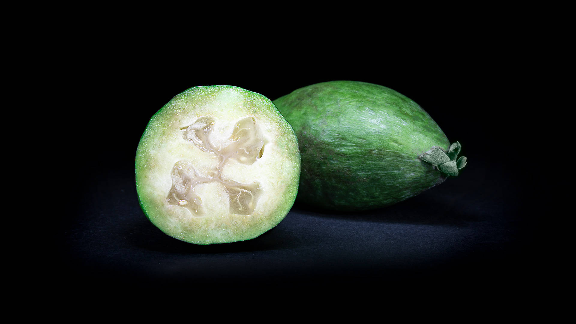 Fruit 桌布 壁紙 — 切片菲油果在純黑背景下展現其星形果芯。