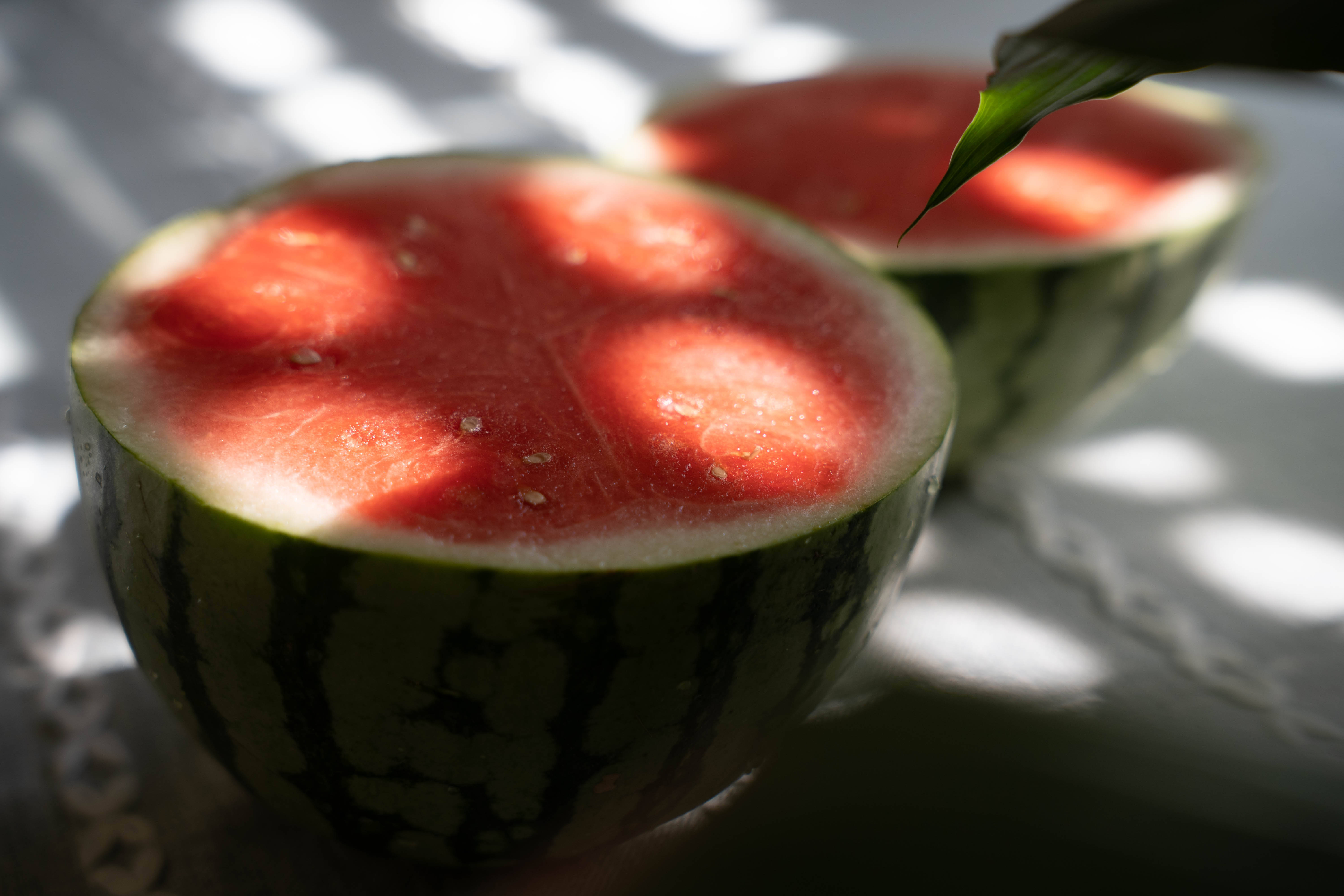 Watermelon 桌布 壁紙 — 切片西瓜沐浴在斑駁的陽光下，在白色蕾絲桌布上投下樹葉般的陰影。