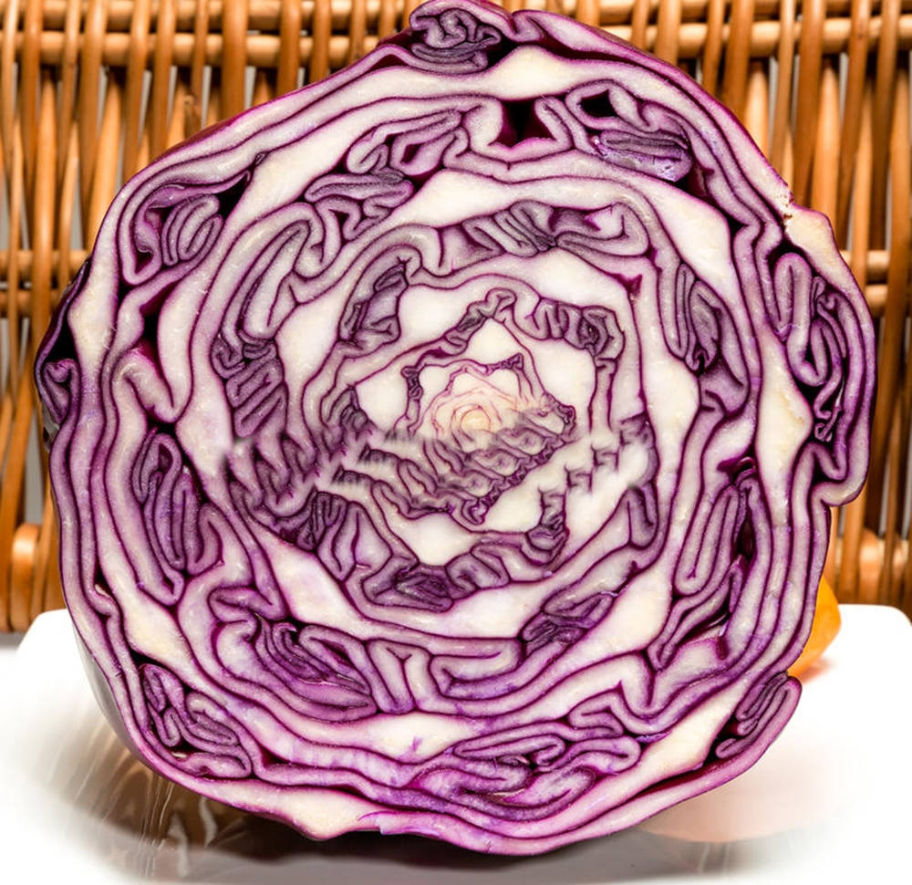 Food Photography 桌布 壁紙 — 切開的紅高麗菜在編織竹背景上展現出複雜的紫色和白色同心層。