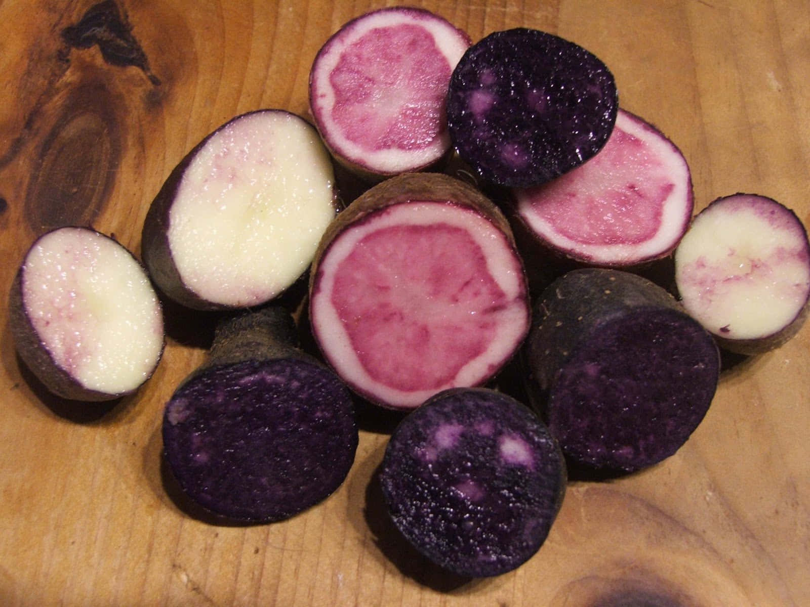 Purple Potato 桌布 壁紙 — 切開的紫薯在質樸的木板上展現出充滿活力的粉紅色和白色內部。