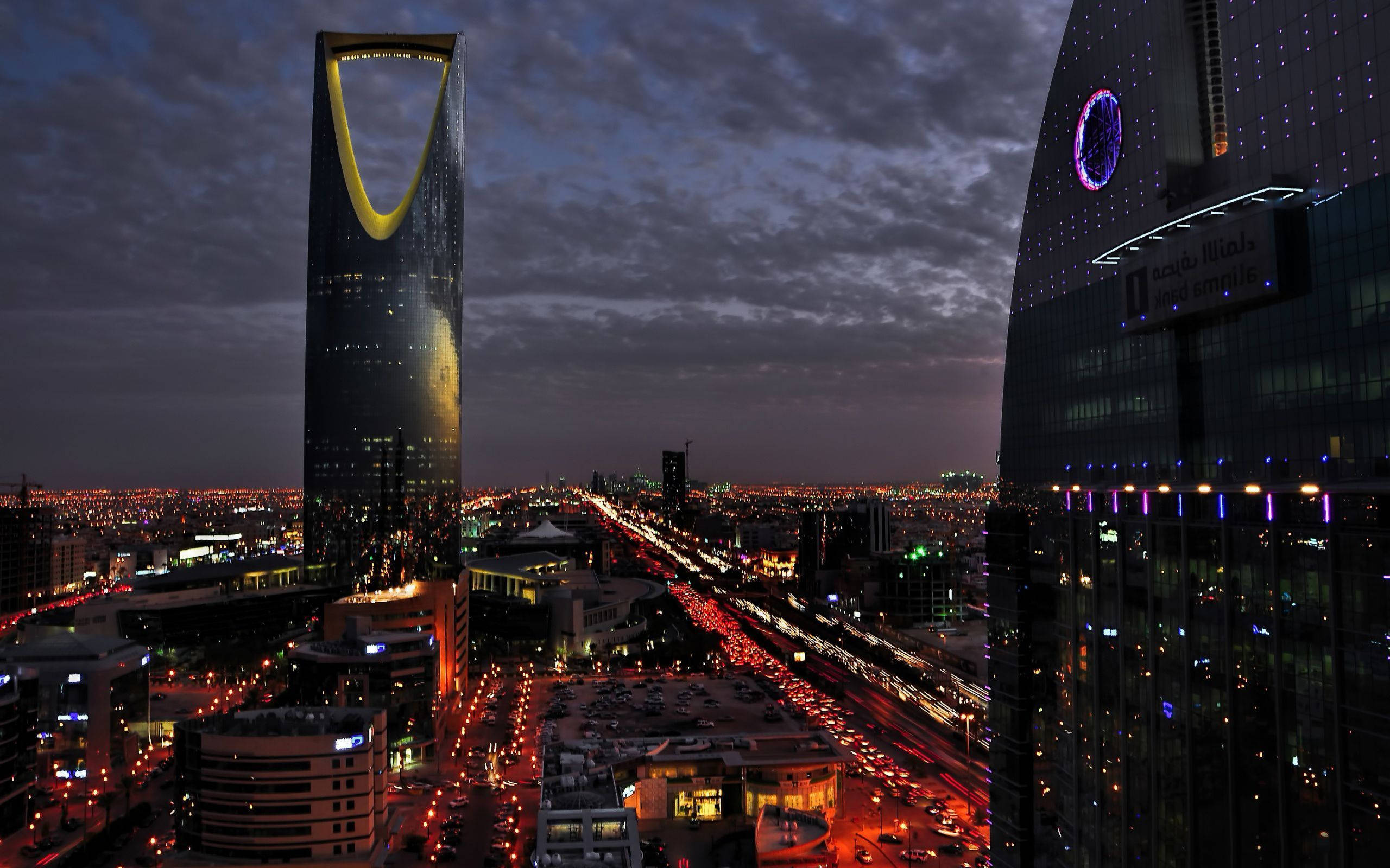 Saudi 桌布 壁紙 — 利雅得天際線在黃昏時的鳥瞰圖，下方有燈火通明的摩天大樓和發光的車流。