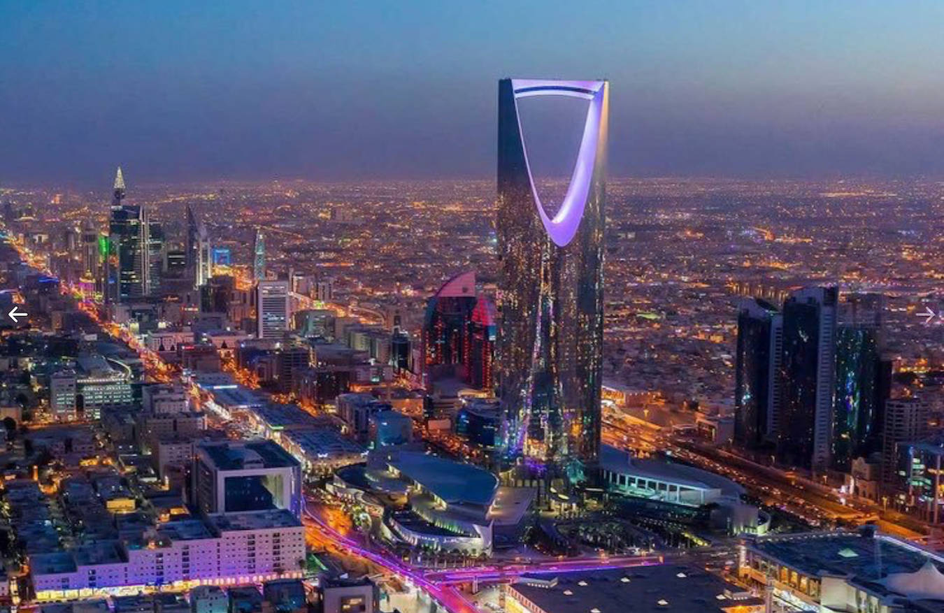 Riyadh 桌布 壁紙 — 利雅得天際線的黃昏航拍圖，王國塔在深藍色天空下發出紫色光芒。