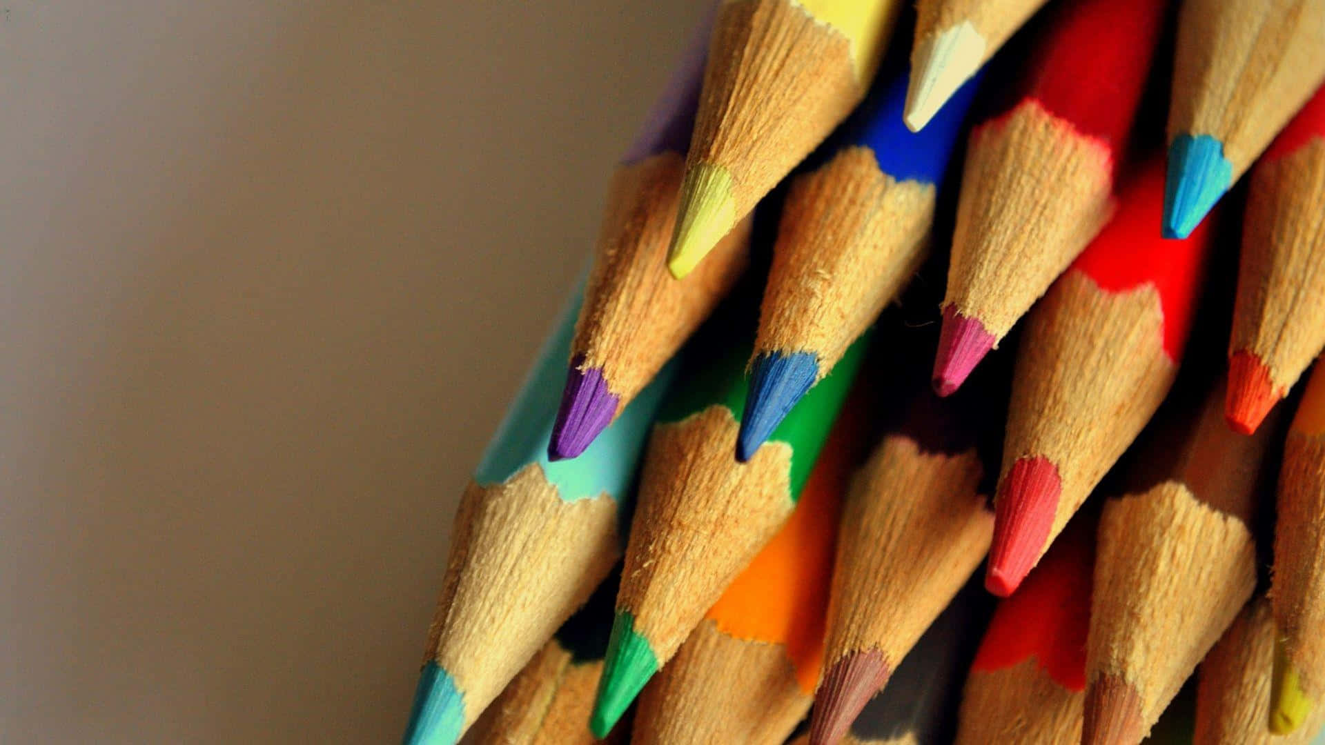 crayon 桌布 壁紙 — 削尖的彩色鉛筆特寫，帶有鮮豔的筆尖，以對角線排列在柔和的米色背景上。