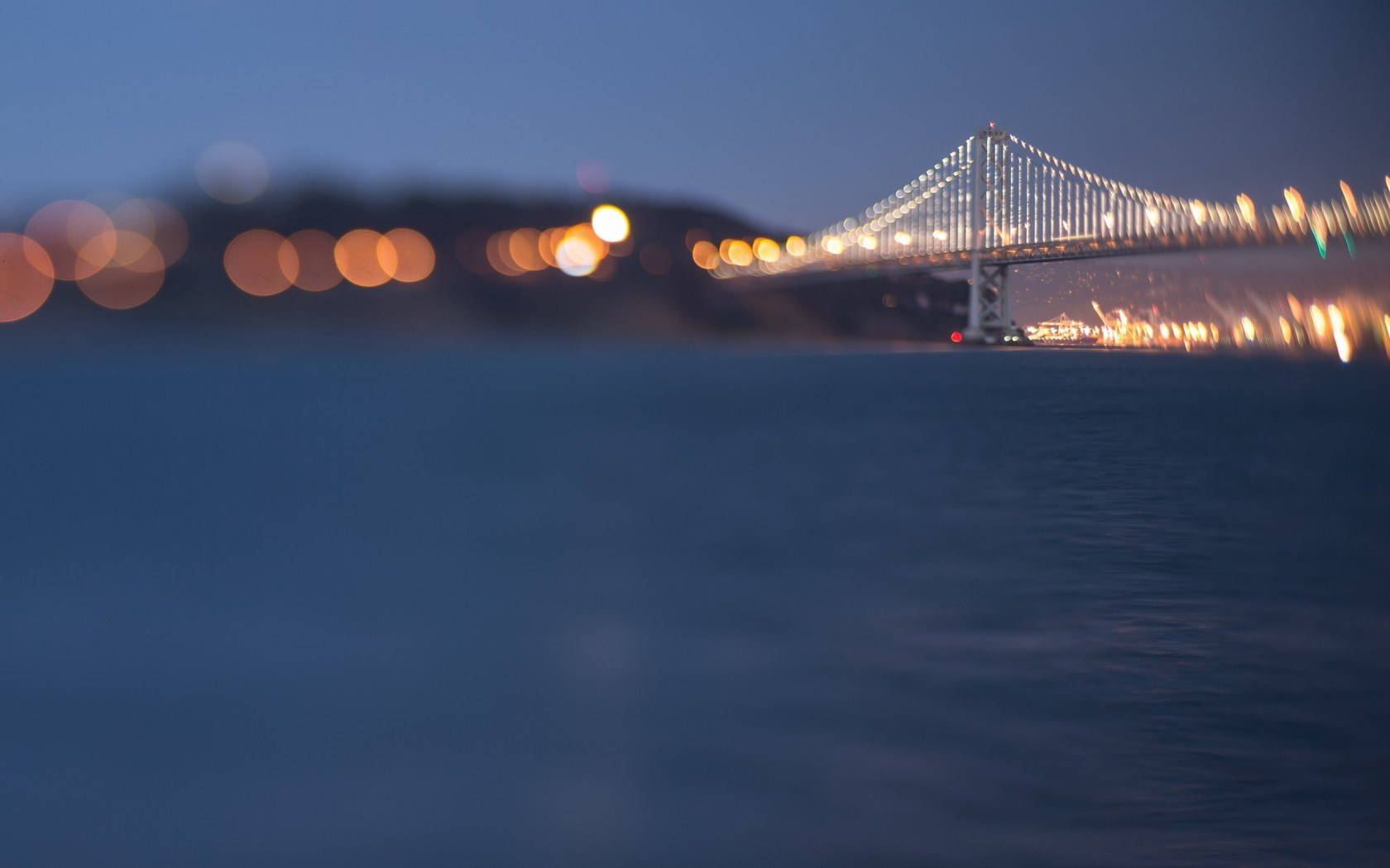 San Francisco HD 桌布 壁紙 — 前景帶有散景燈光，水面上發光的吊橋的柔和模糊黃昏景色。