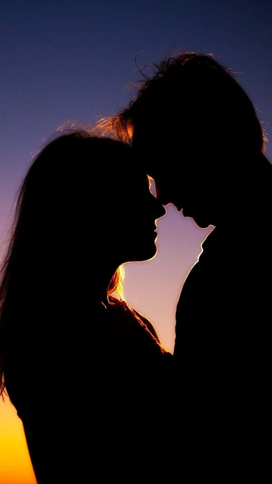 lover 桌布 壁紙 — 剪影中的情侶在充滿活力的日落天空下溫柔擁抱，頭髮閃耀著光芒。