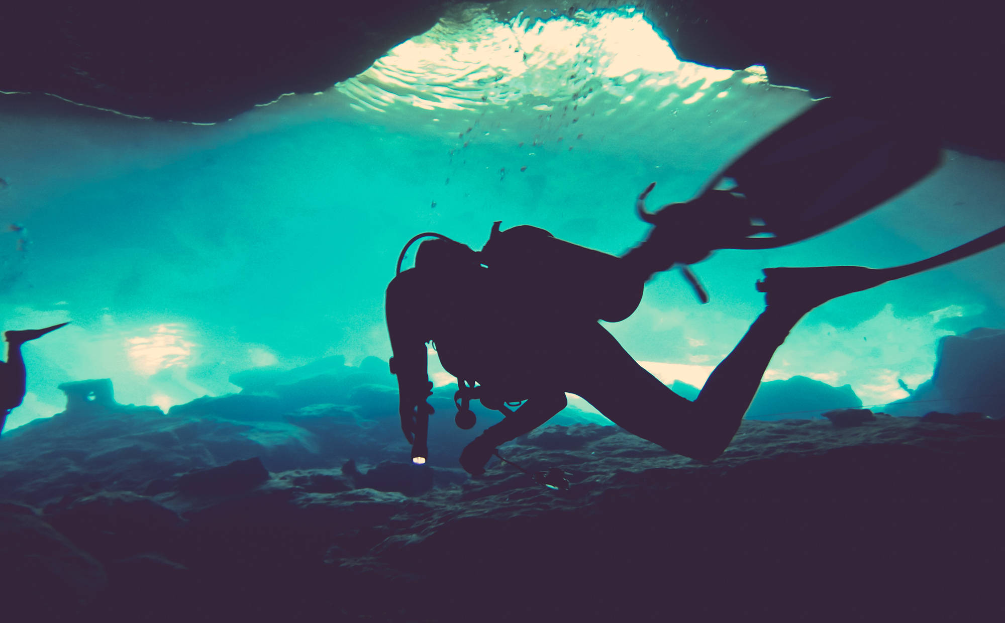 diving 桌布 壁紙 — 剪影中的水肺潛水員探索水下洞穴，陽光從上方穿透而下。