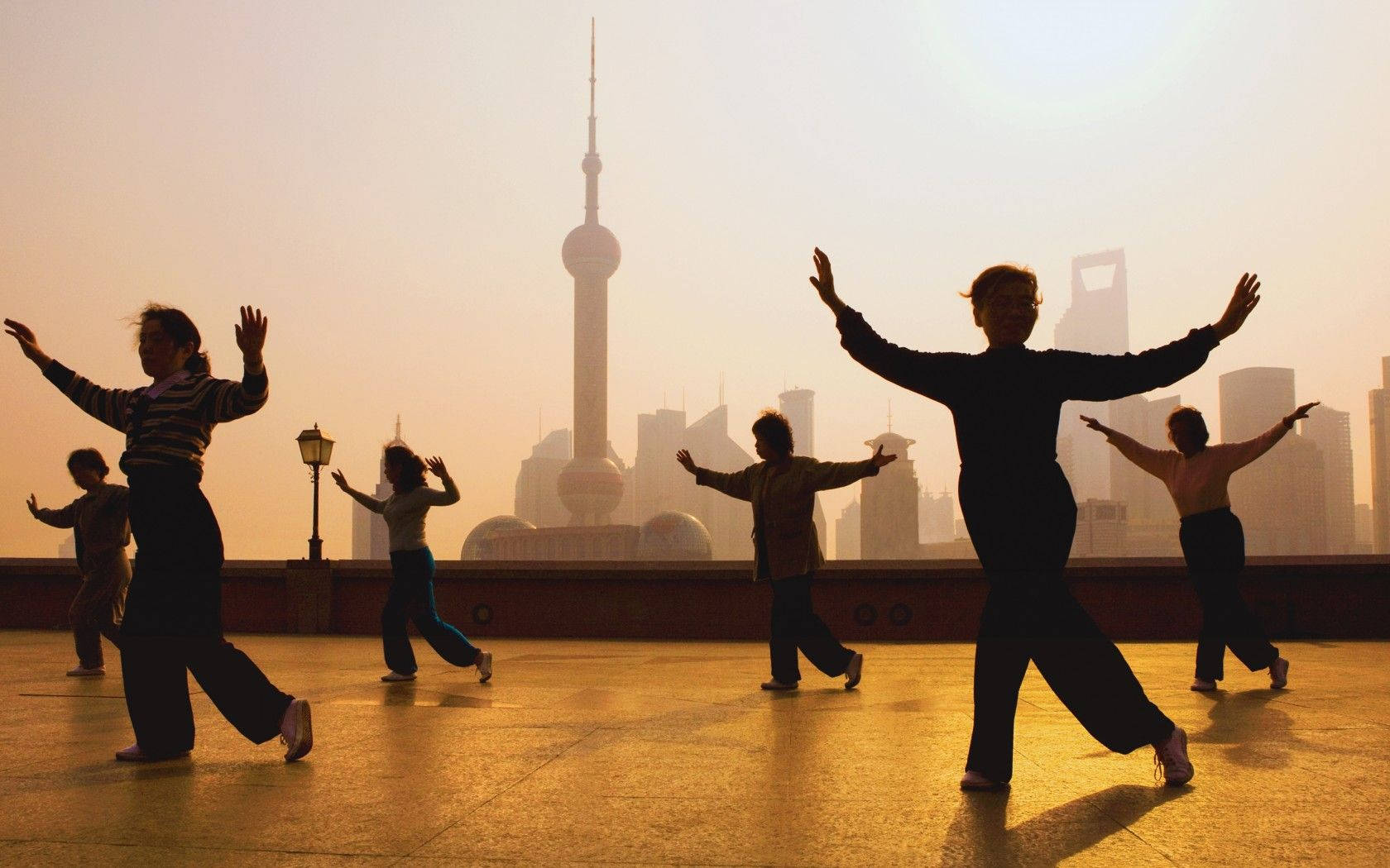 Exercise 桌布 壁紙 — 剪影人物在廣場上練習同步舞蹈動作，太陽在上海標誌性天際線後落下。