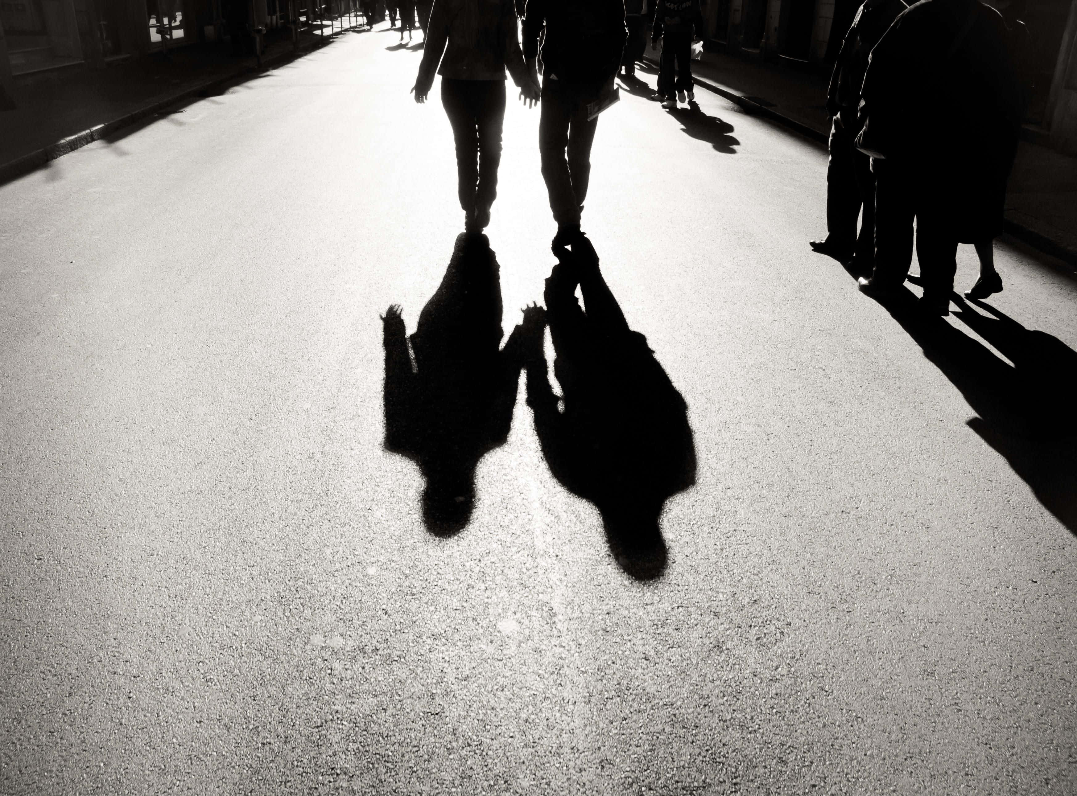 shadow 桌布 壁紙 — 剪影人物手牽手走在陽光明媚的街道上，他們拉長的影子延伸在人行道上。
