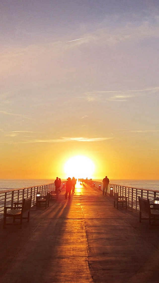 End Of Summer 桌布 壁紙 — 剪影人物沿著碼頭漫步，太陽在海洋上空燃燒成橙色和金色。