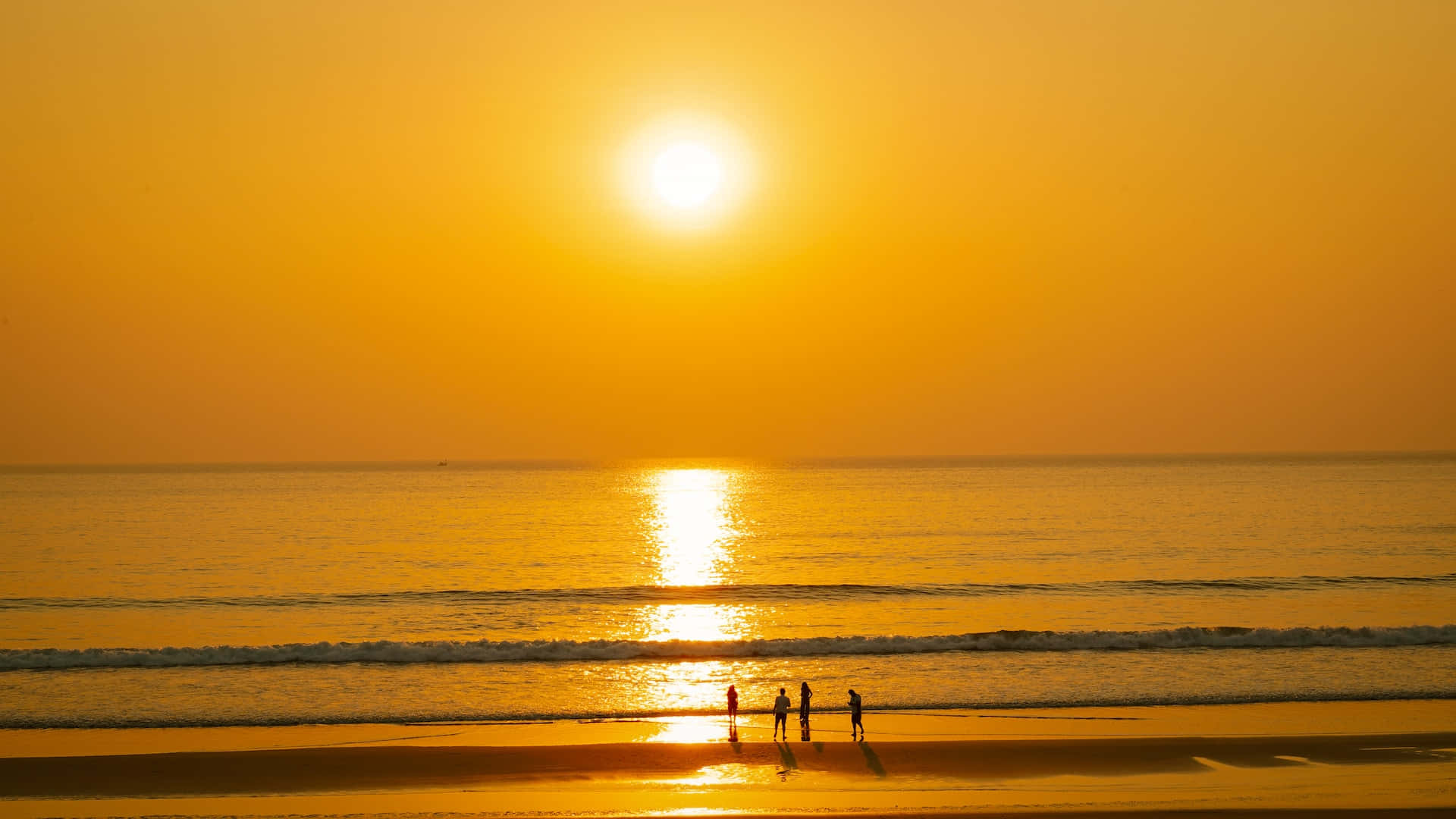 Yellow Beach 桌布 壁紙 — 剪影人物沿著金色沙灘行走，夕陽在平靜的海面上落下。