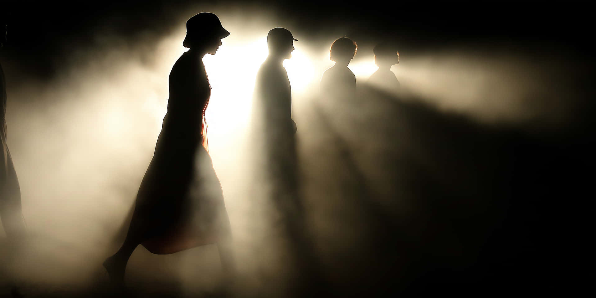 Shadowed Figures 壁紙 — 剪影人物穿過濃霧，被戲劇性的背光照射，形成長長的影子。