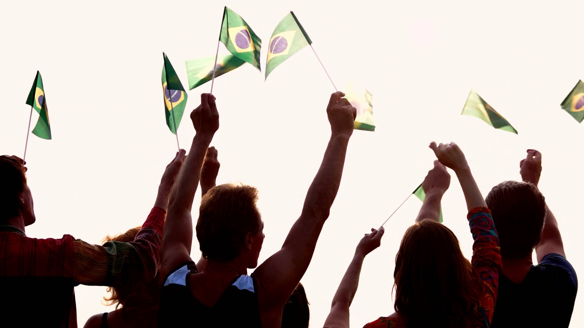 Brazil Flag 桌布 壁紙 — 剪影人群在明亮的天空下歡快地舉起巴西國旗。