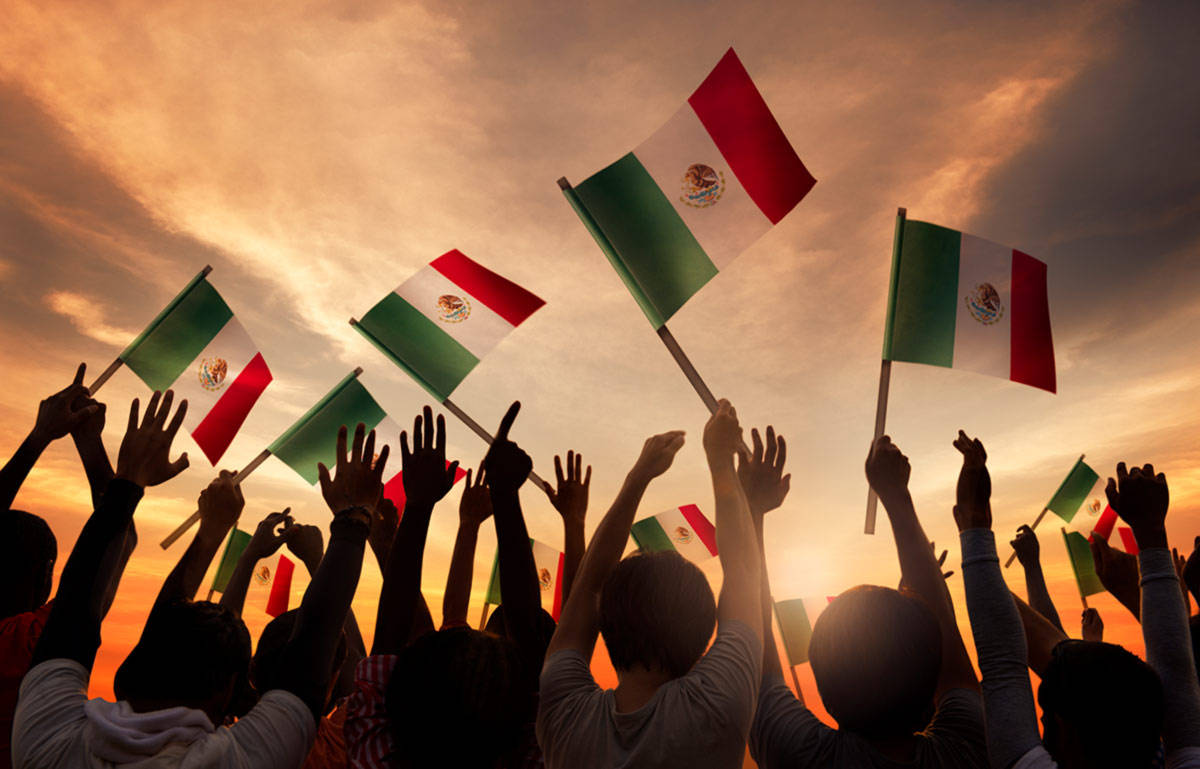 Mexican 桌布 壁紙 — 剪影人群在熾熱的日落天空下揮舞墨西哥國旗，展現充滿活力的愛國展示。