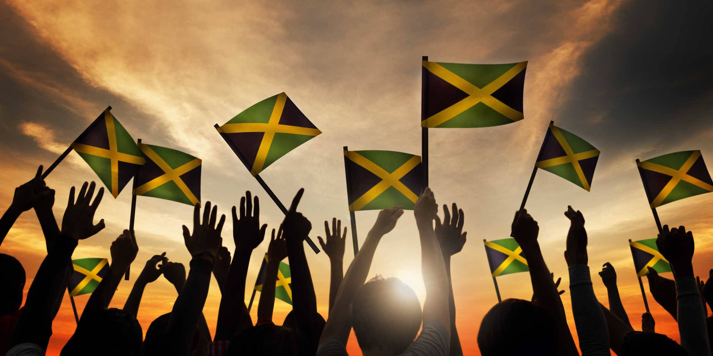 Jamaica 桌布 壁紙 — 剪影人群在熾熱的日落天空下揮舞牙買加國旗。