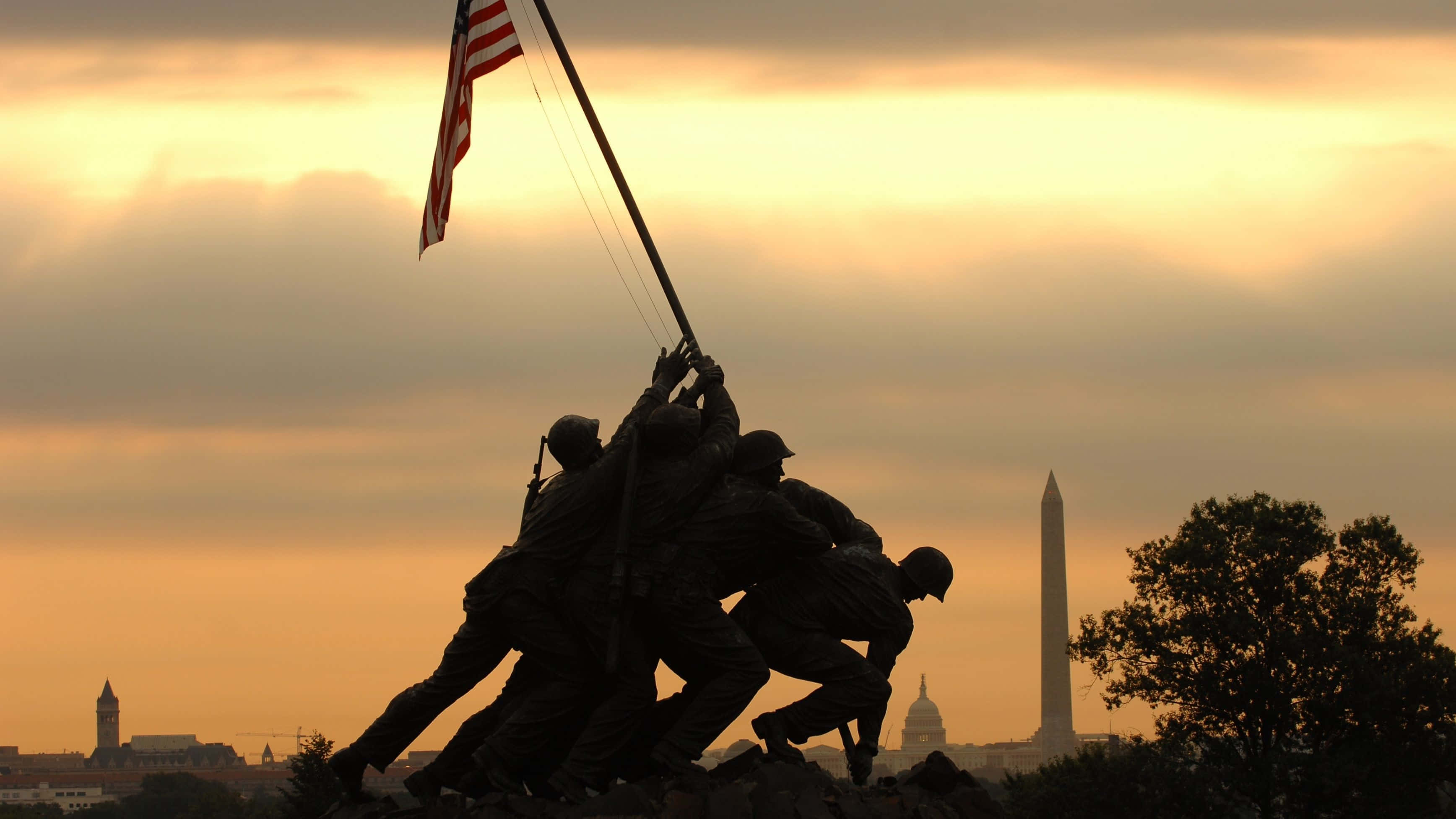 United States 桌布 壁紙 — 剪影士兵在日落時分於紀念碑頂升起美國國旗，背景是華盛頓紀念碑。