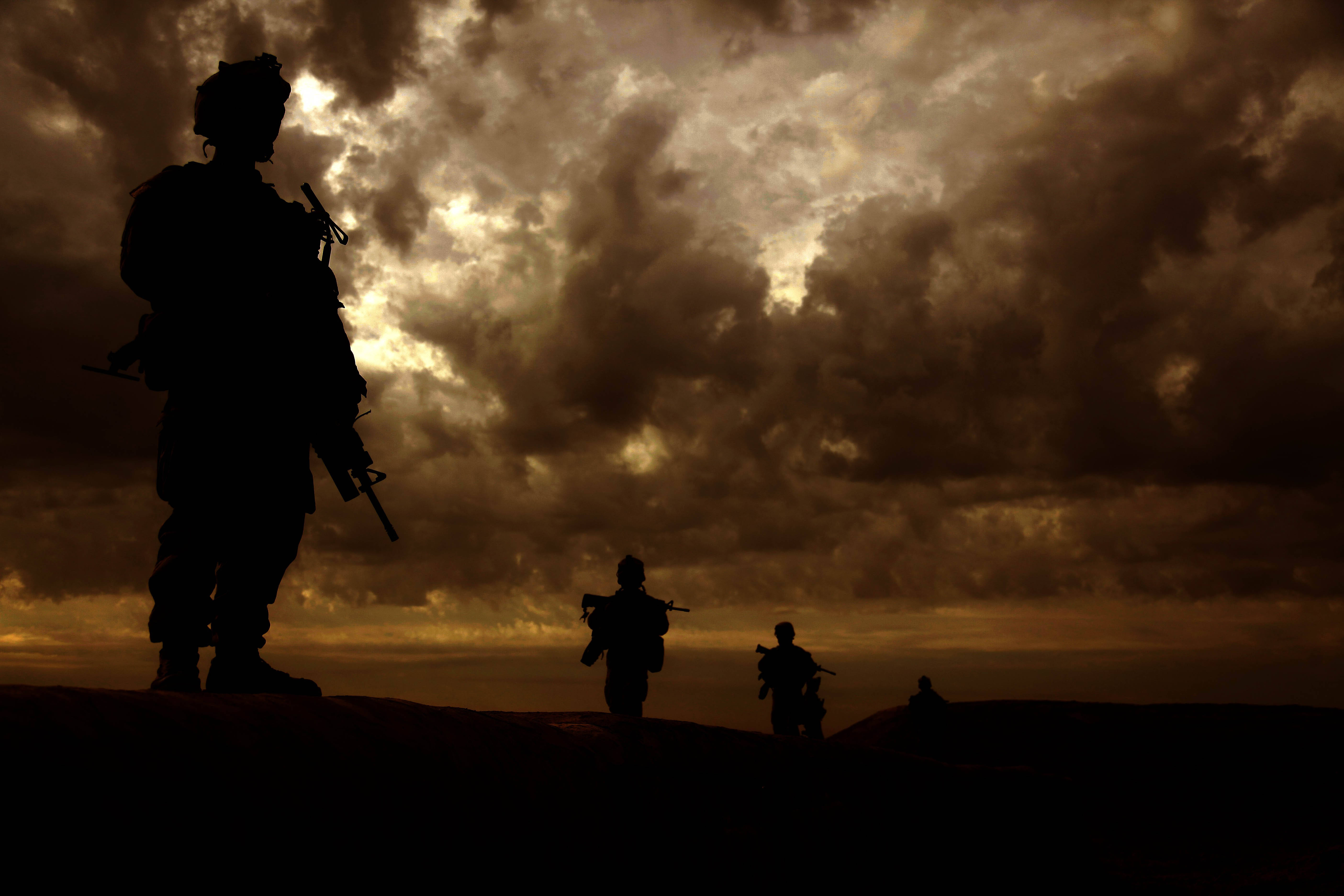 Afghanistan 桌布 壁紙 — 剪影士兵站在充滿紋理雲彩的戲劇性金色日落天空前。