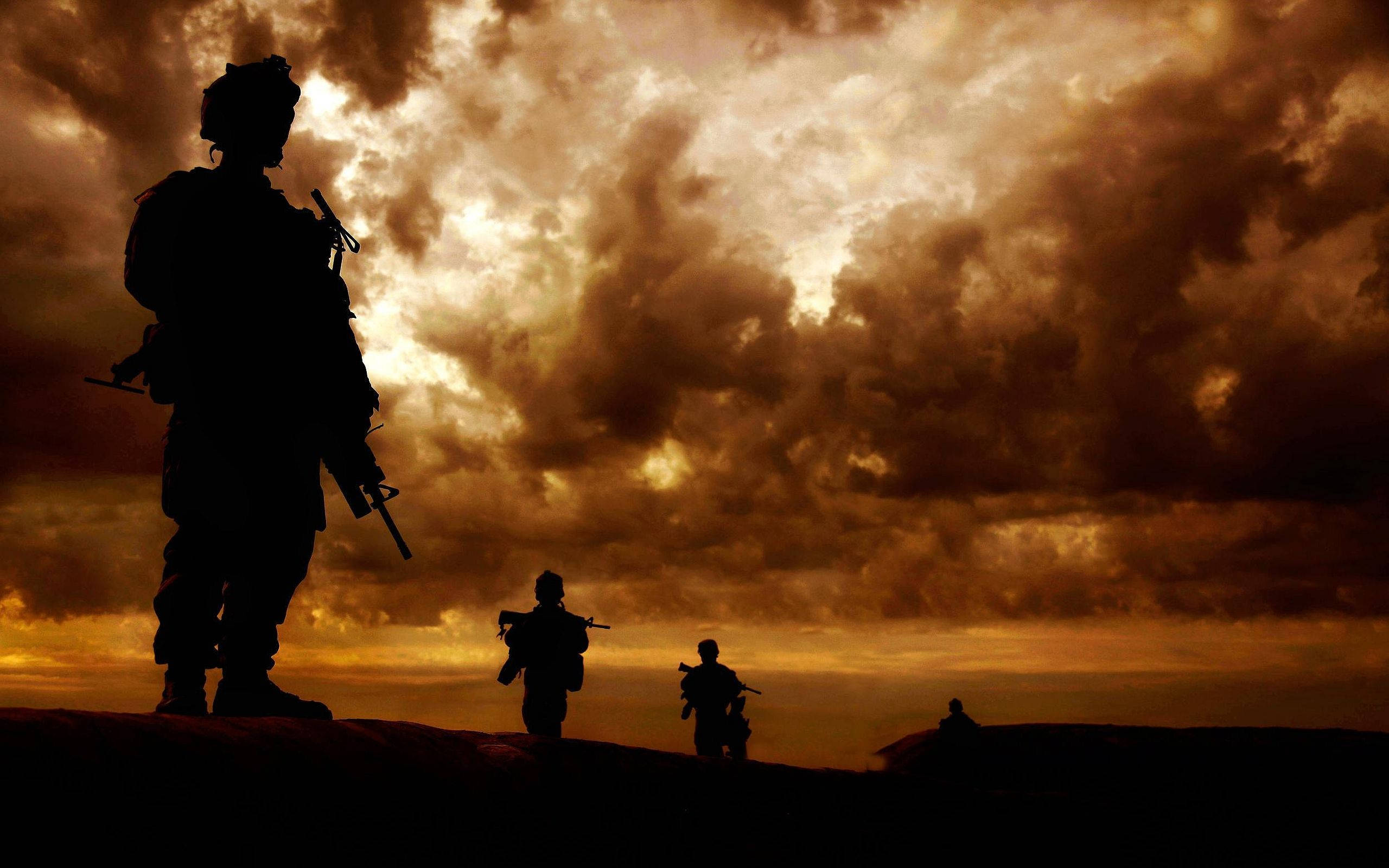 軍隊 桌布 壁紙 — 剪影士兵站在充滿紋理雲彩的戲劇性金色日落天空前。