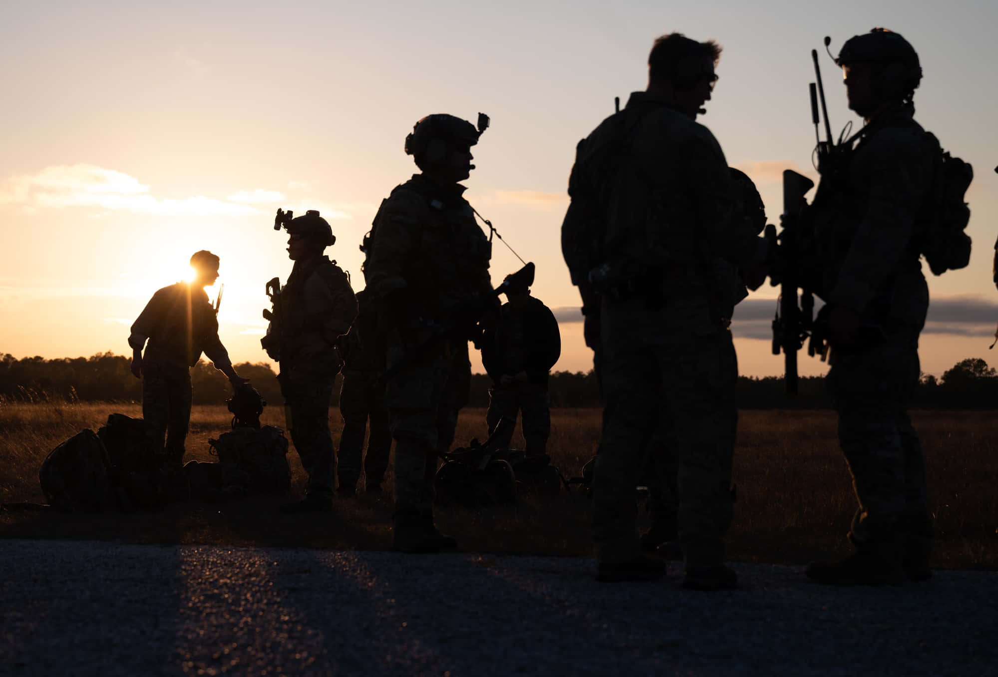 Silhouette 桌布 壁紙 — 剪影士兵站在田野中，夕陽在他們身後散發溫暖的金色光芒。