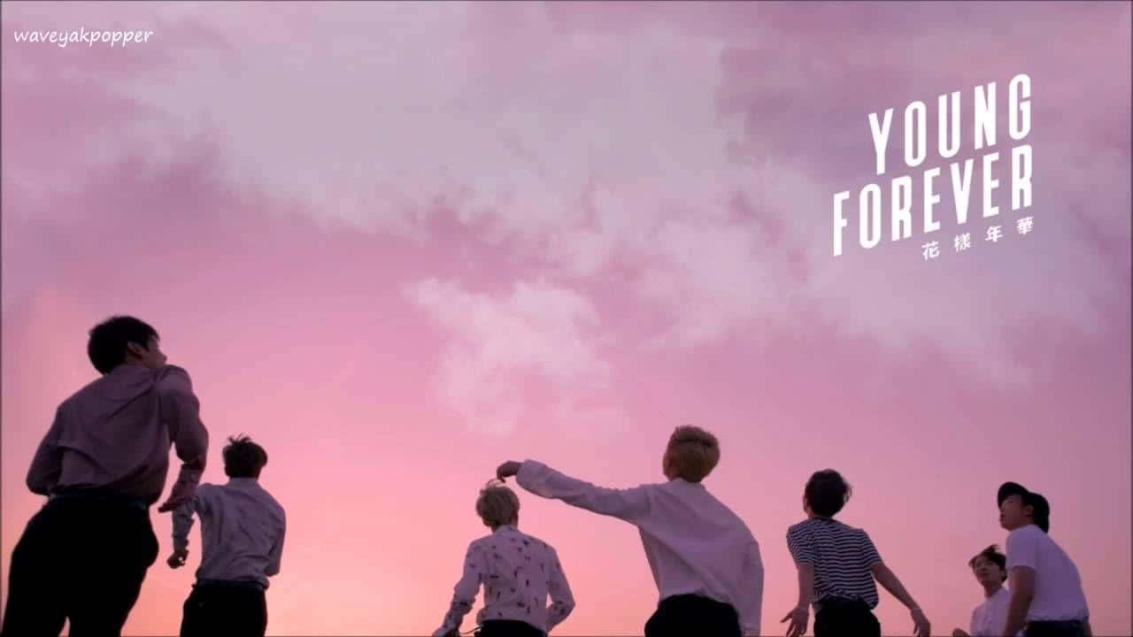 桌布 壁紙 — 剪影年輕男子站在柔和的粉紅色日落天空下，『YOUNG FOREVER』字樣漂浮在他們上方。