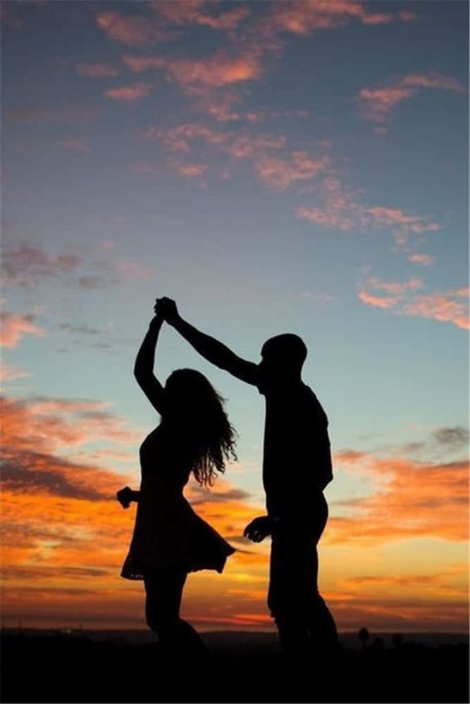 Girlfriend And Boyfriend 桌布 壁紙 — 剪影情侶在充滿活力的日落天空下快樂地跳舞，天空帶有橙色、粉紅色和藍色的條紋。