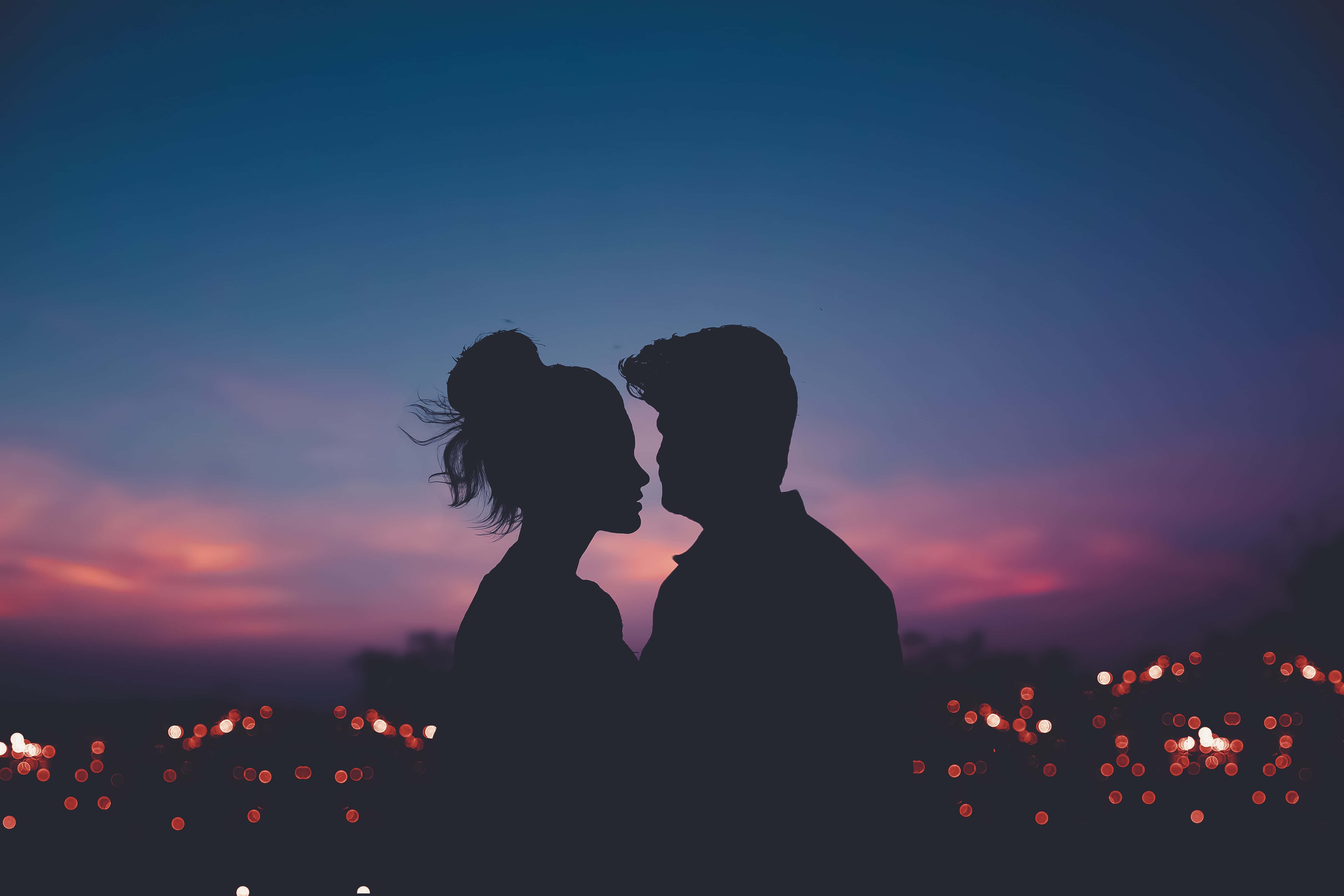Love Couple 桌布 壁紙 — 剪影情侶在帶有紫色和橙色條紋的暮色天空下分享親密時刻。