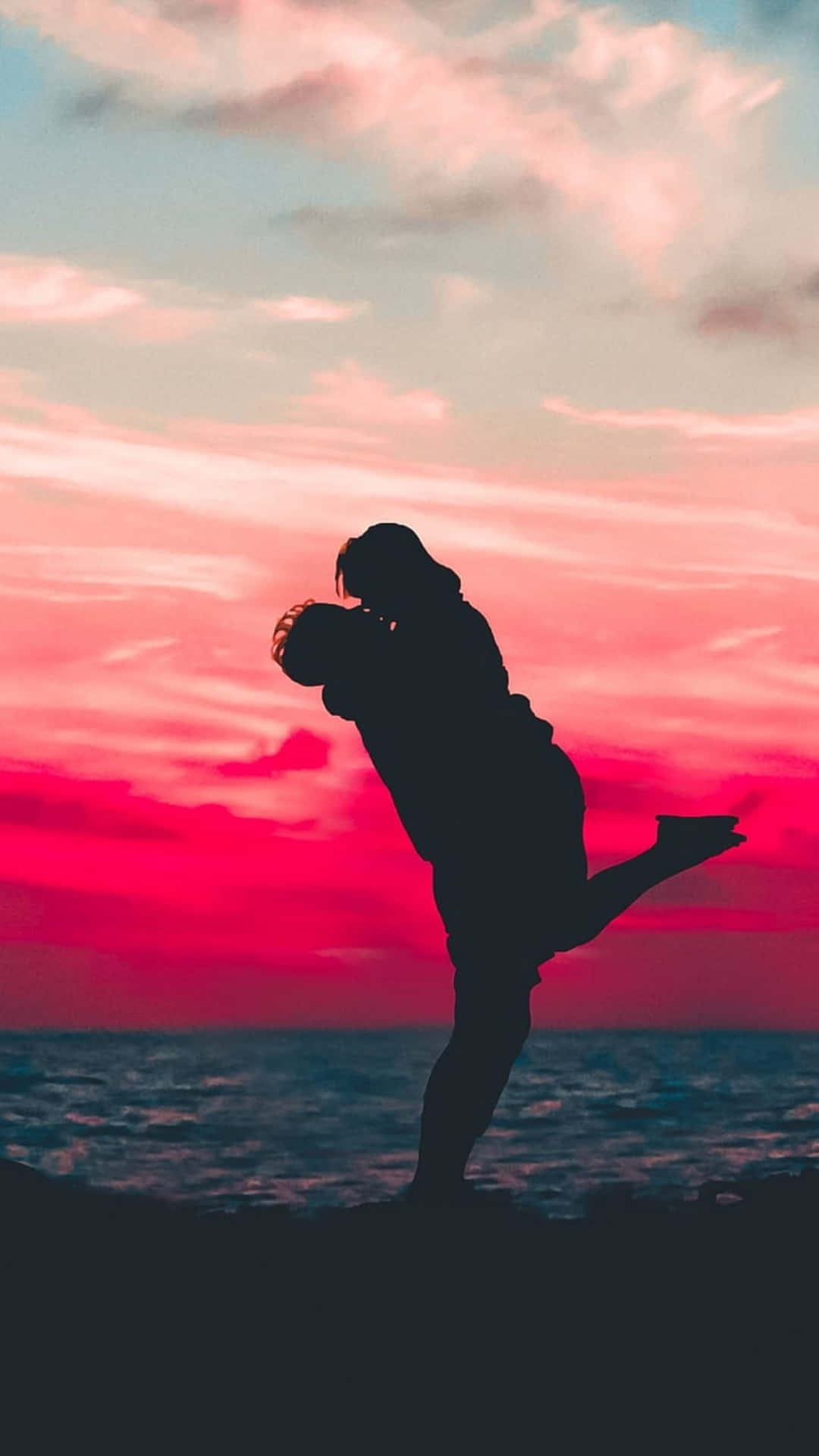 Lovers 桌布 壁紙 — 剪影情侶在懸崖邊熱情擁抱，熾熱的夕陽將天空染成鮮豔的粉紅色和橙色。
