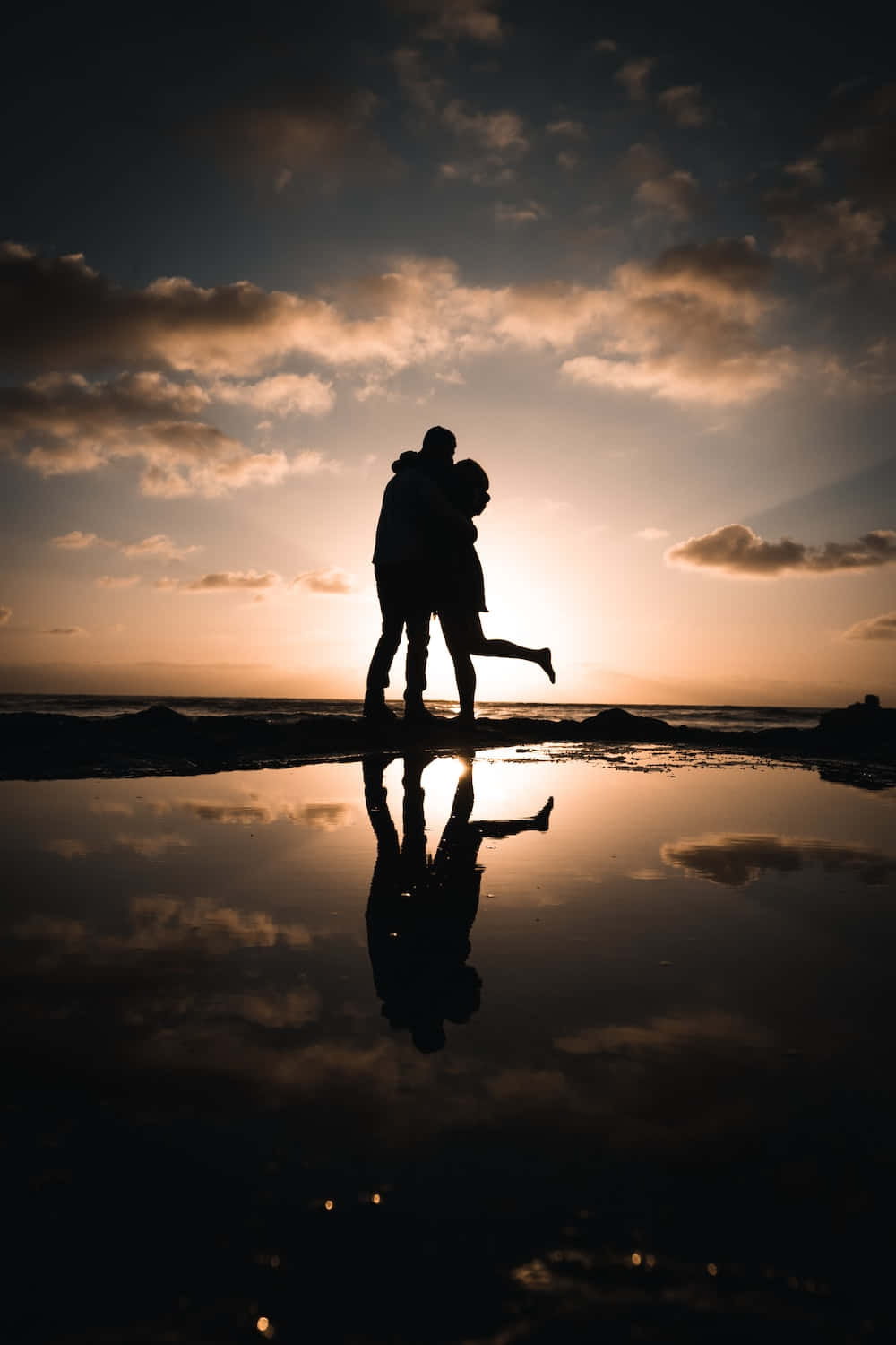 Beautiful Couple 桌布 壁紙 — 剪影情侶在日落時分的沙灘上擁抱，潮汐池中完美倒影。
