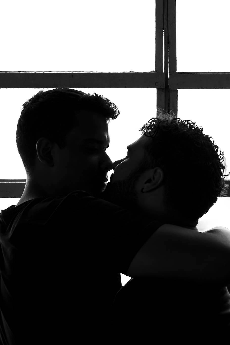 gay kiss 桌布 壁紙 — 剪影情侶在明亮的窗戶前溫柔擁抱，構成強烈的黑白畫面。