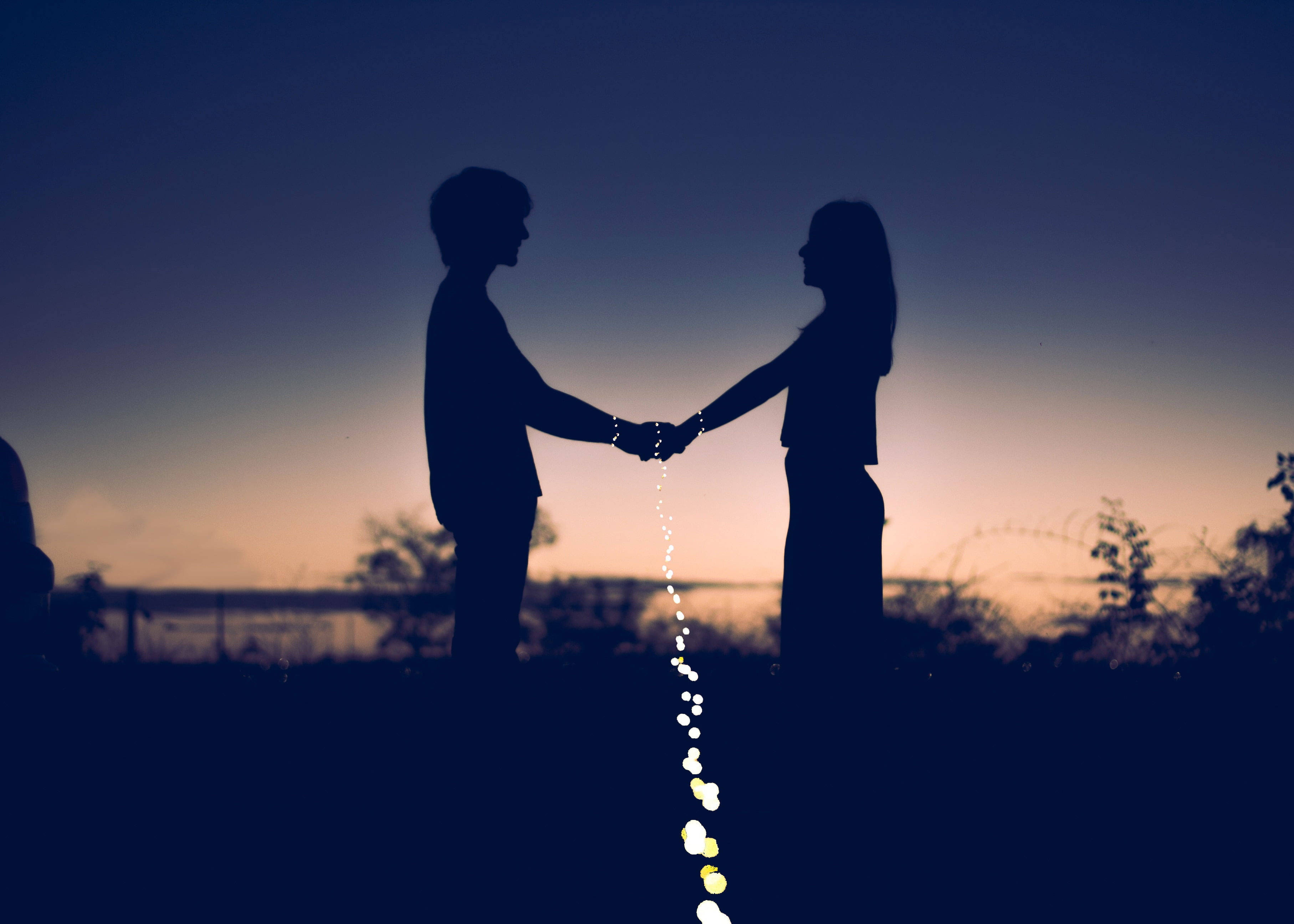 Silhouette 桌布 壁紙 — 剪影情侶在暮色天空下手牽手，發光的燈串連接著他們。