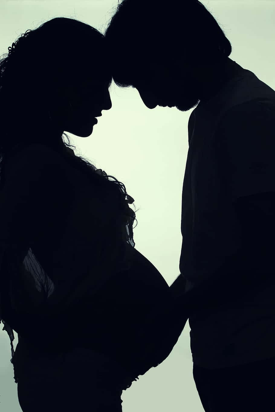 Silhouette 桌布 壁紙 — 剪影情侶在柔和發光背景前溫柔擁抱，額頭親密相觸。