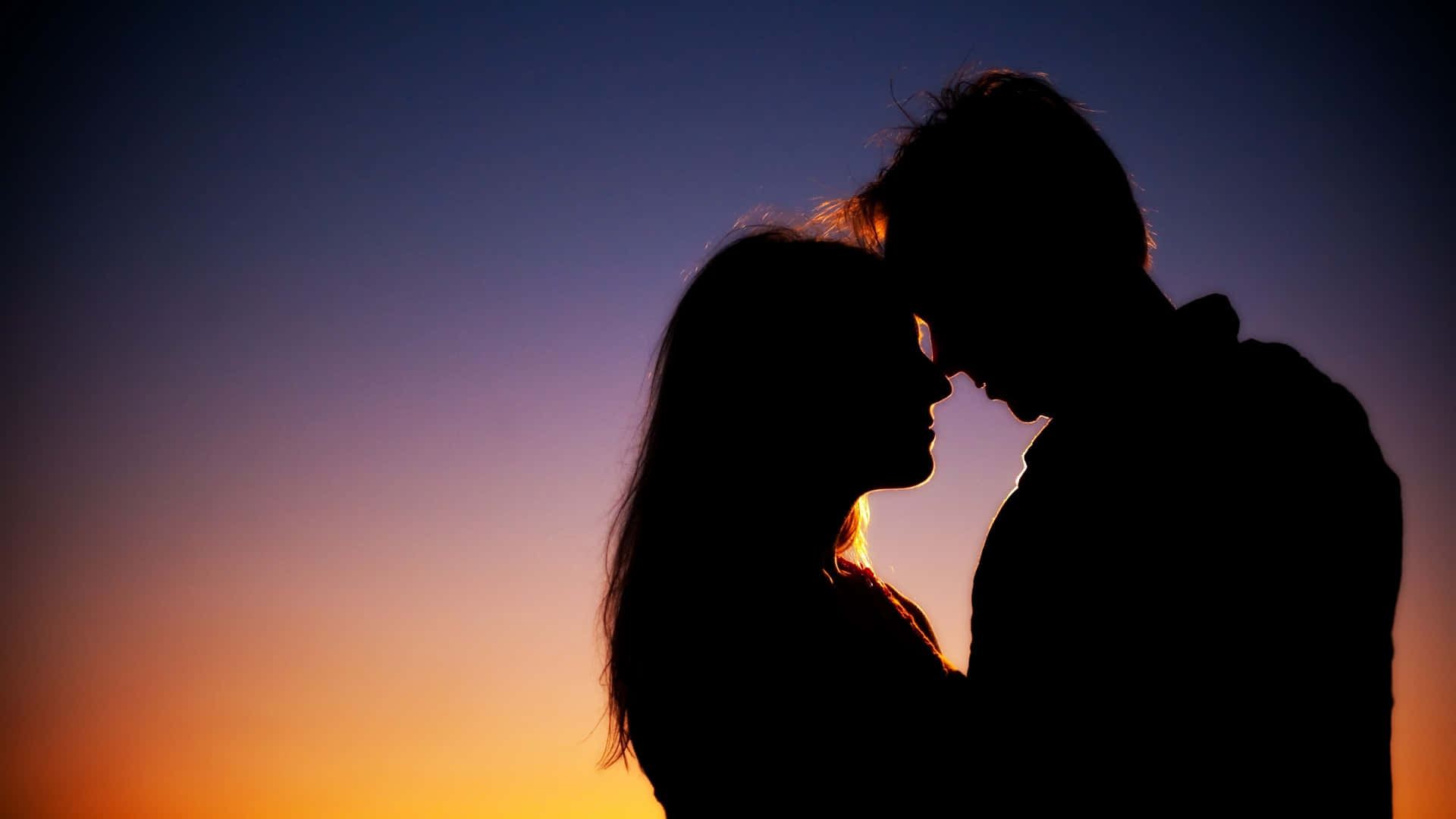 Beautiful Love 桌布 壁紙 — 剪影情侶在溫暖橙色和清涼藍色漸變的鮮豔日落天空下溫柔擁抱。