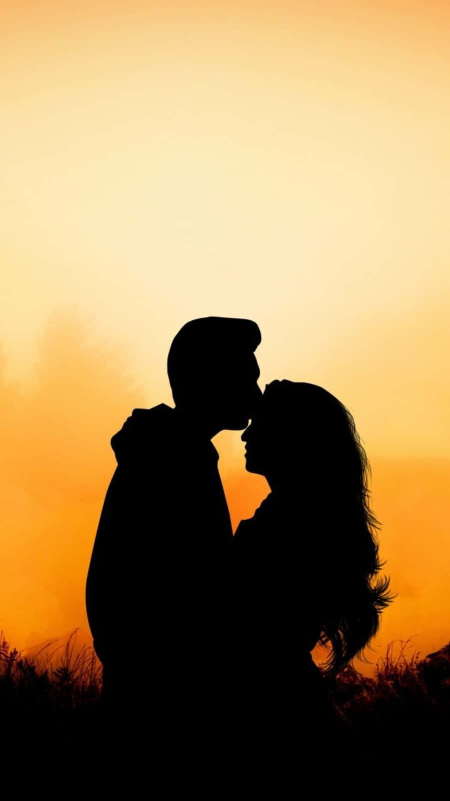 lover 桌布 壁紙 — 剪影情侶在溫暖的金色日落天空下分享溫柔的親吻。