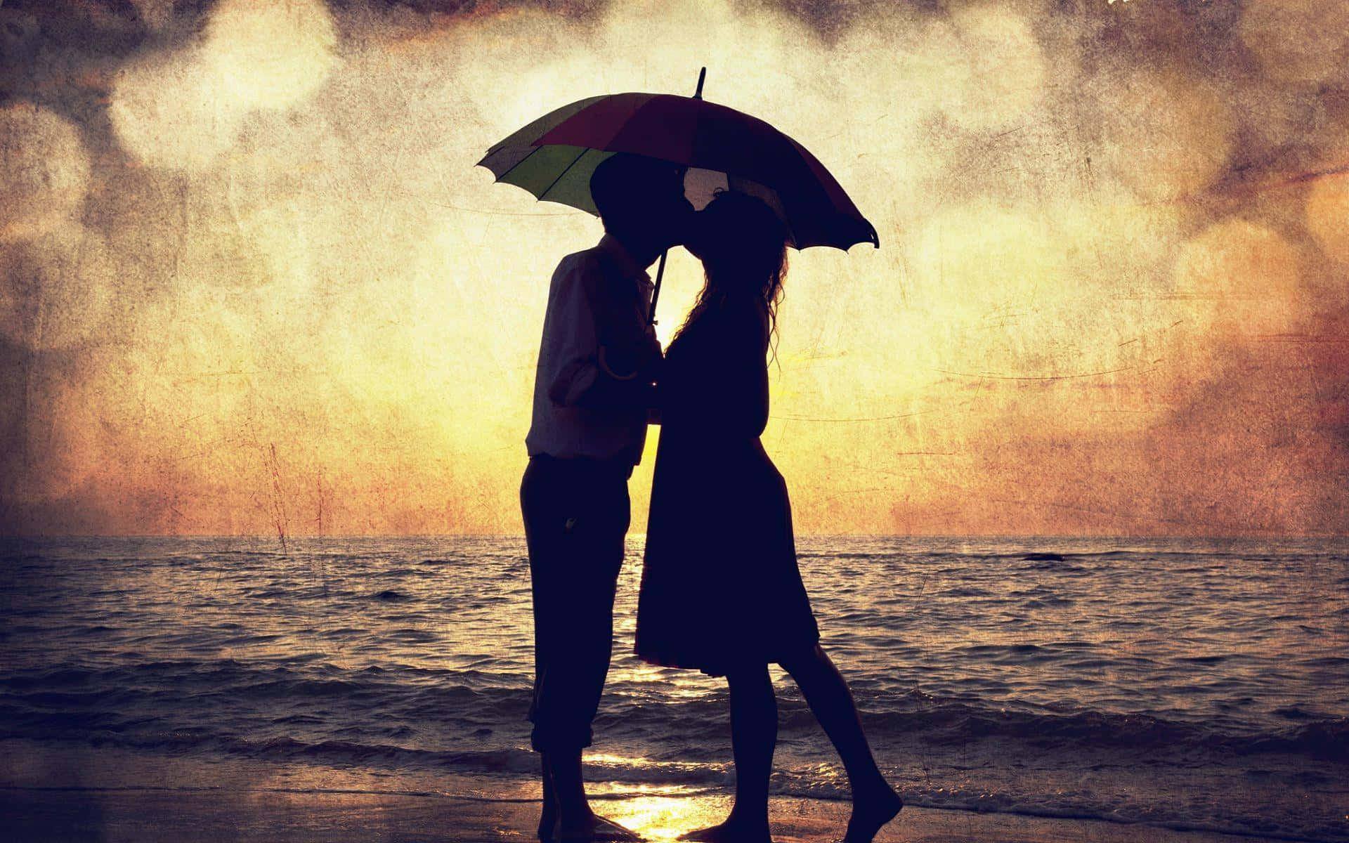 Silhouette 桌布 壁紙 — 剪影情侶在金色日落時分的雨灘上，在彩色雨傘下接吻。