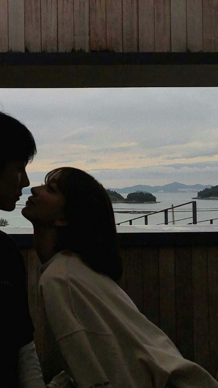 Couples 桌布 壁紙 — 剪影情侶在霧氣瀰漫的海岸背景、遠處島嶼和陰天中深情對望。