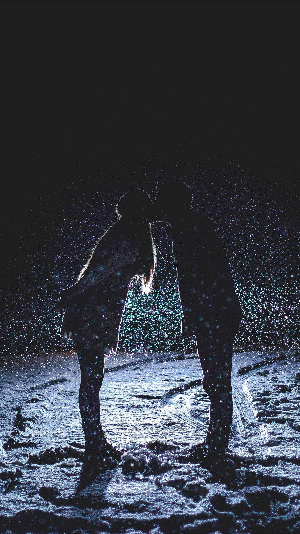 Love Story 桌布 壁紙 — 剪影情侶在黑暗的冬夜中，於飄雪下親吻，周圍有發光的粒子。