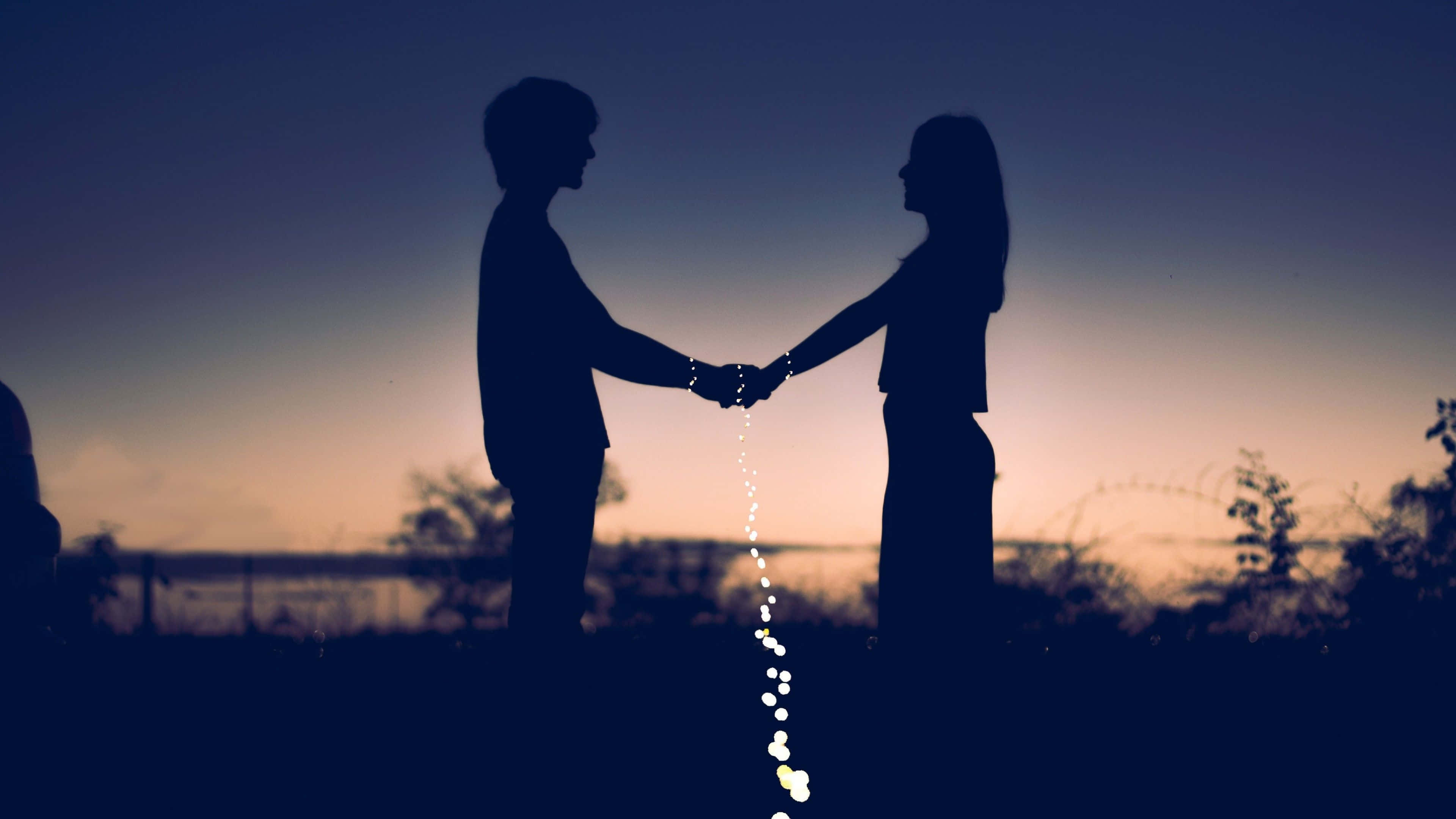 couple love 桌布 壁紙 — 剪影情侶手牽手，發光燈光在他們之間如瀑布般流下，映襯著暮色天空。