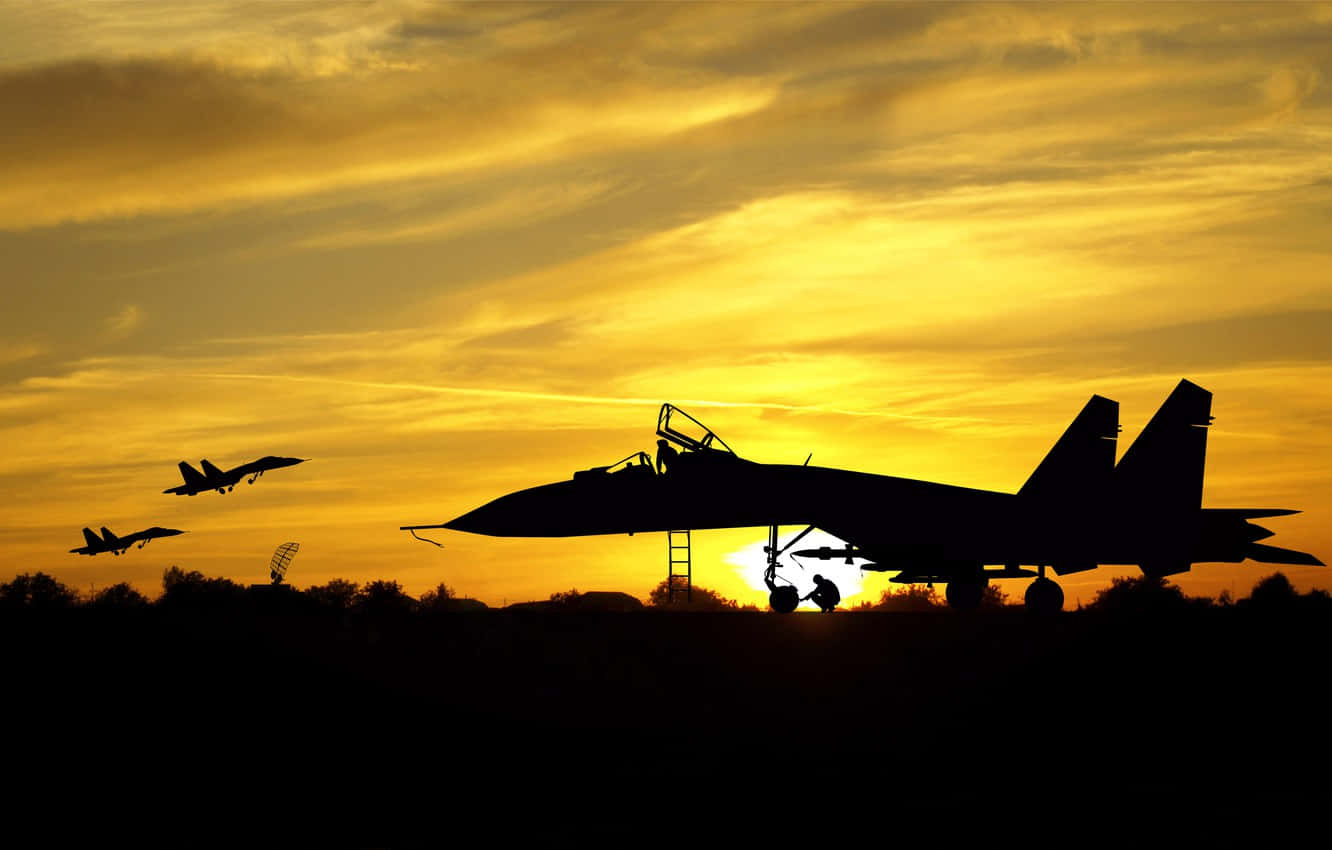 Silhouette 桌布 壁紙 — 剪影戰鬥機主宰金色日落天空，其中一架停在地面，附近有技術人員。