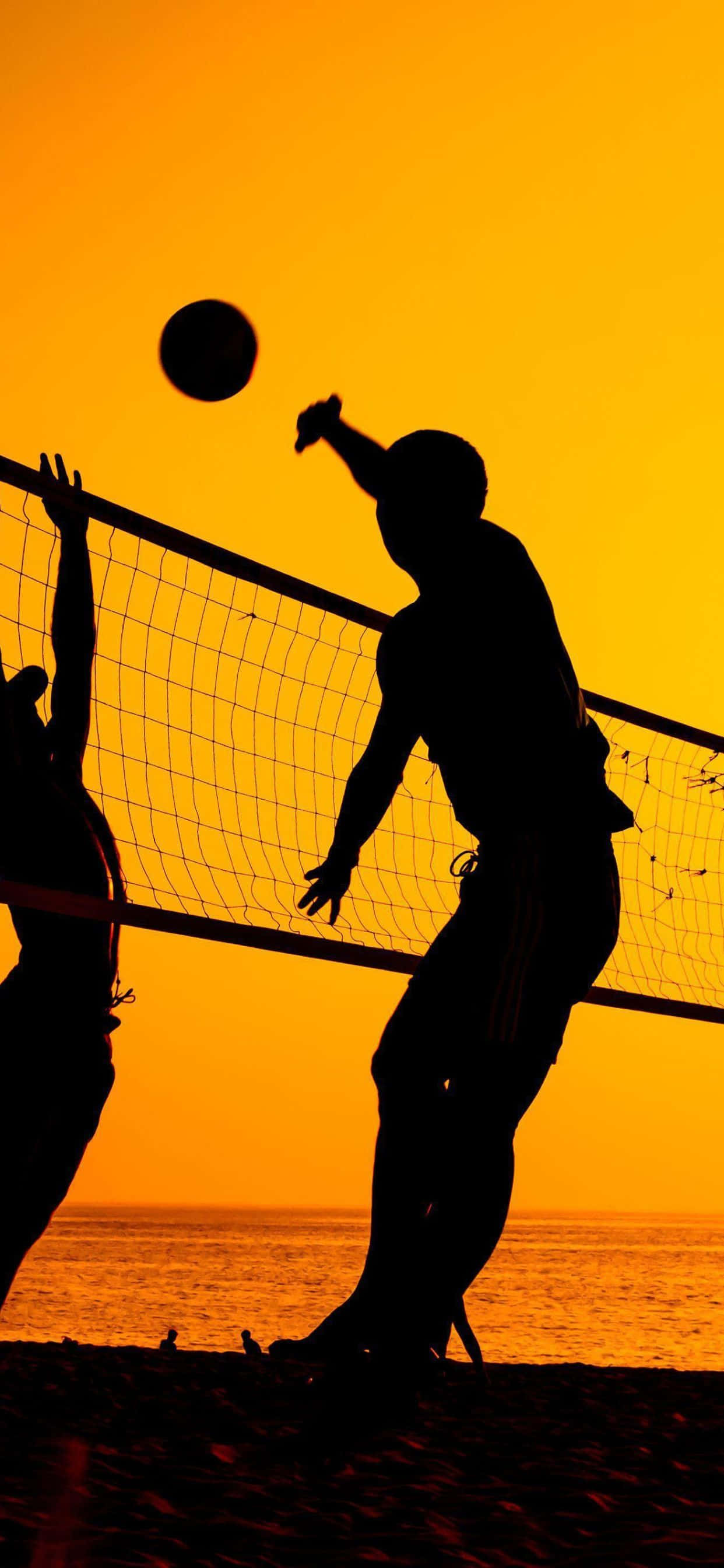 iPhone Xs Max Volleyball 桌布 壁紙 — 剪影沙灘排球運動員跳起並擊球，背景是火紅的橙色日落天空。