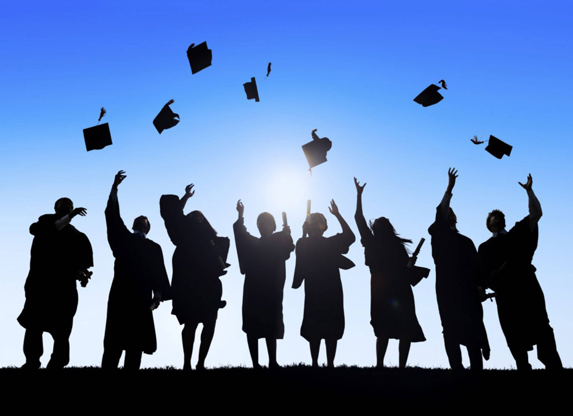 Graduation 桌布 壁紙 — 剪影畢業生在日落時分開心地將學士帽拋向明亮的藍天。