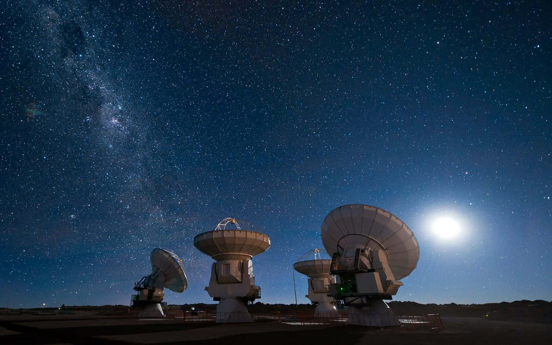 Space Observation 桌布 壁紙 — 剪影的無線電望遠鏡矗立在繁星點點的夜空下，銀河和明亮的月亮在上方閃耀。