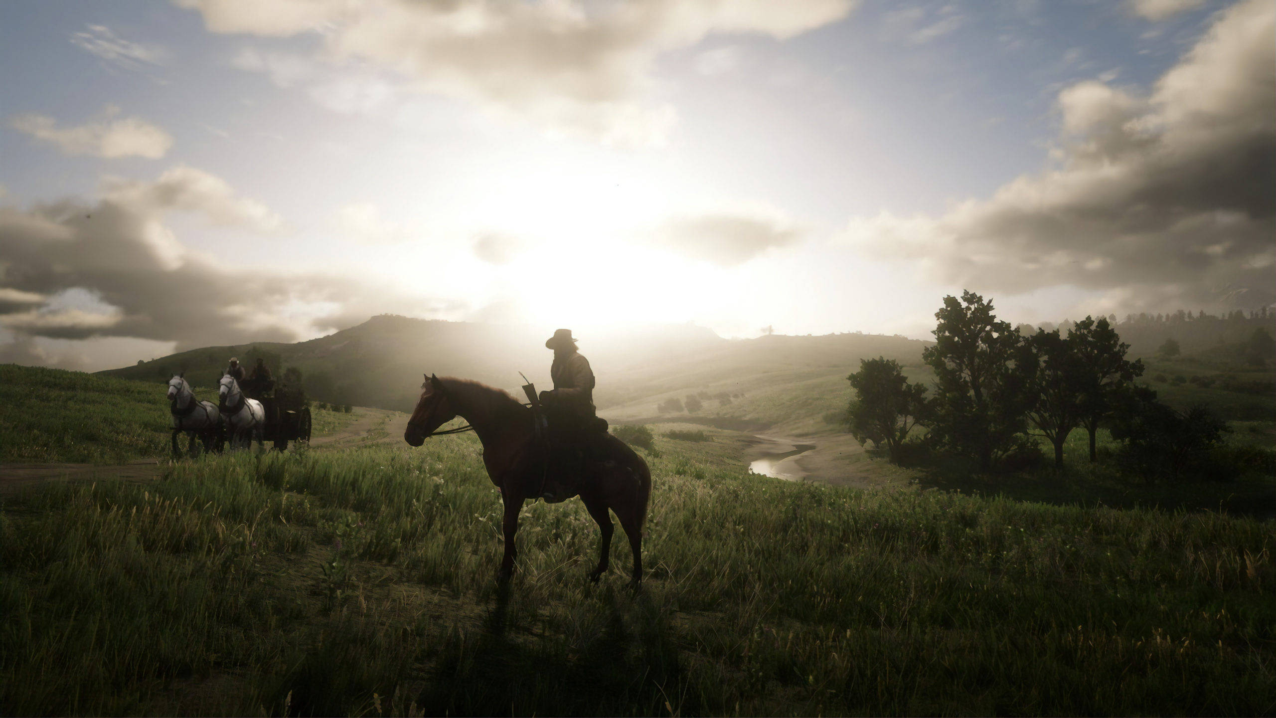 Red Dead Redemption 2 Desktop 桌布 壁紙 — 剪影的牛仔騎著馬，在陽光照耀的草地上穿越，天空多雲，遠處有山脈。