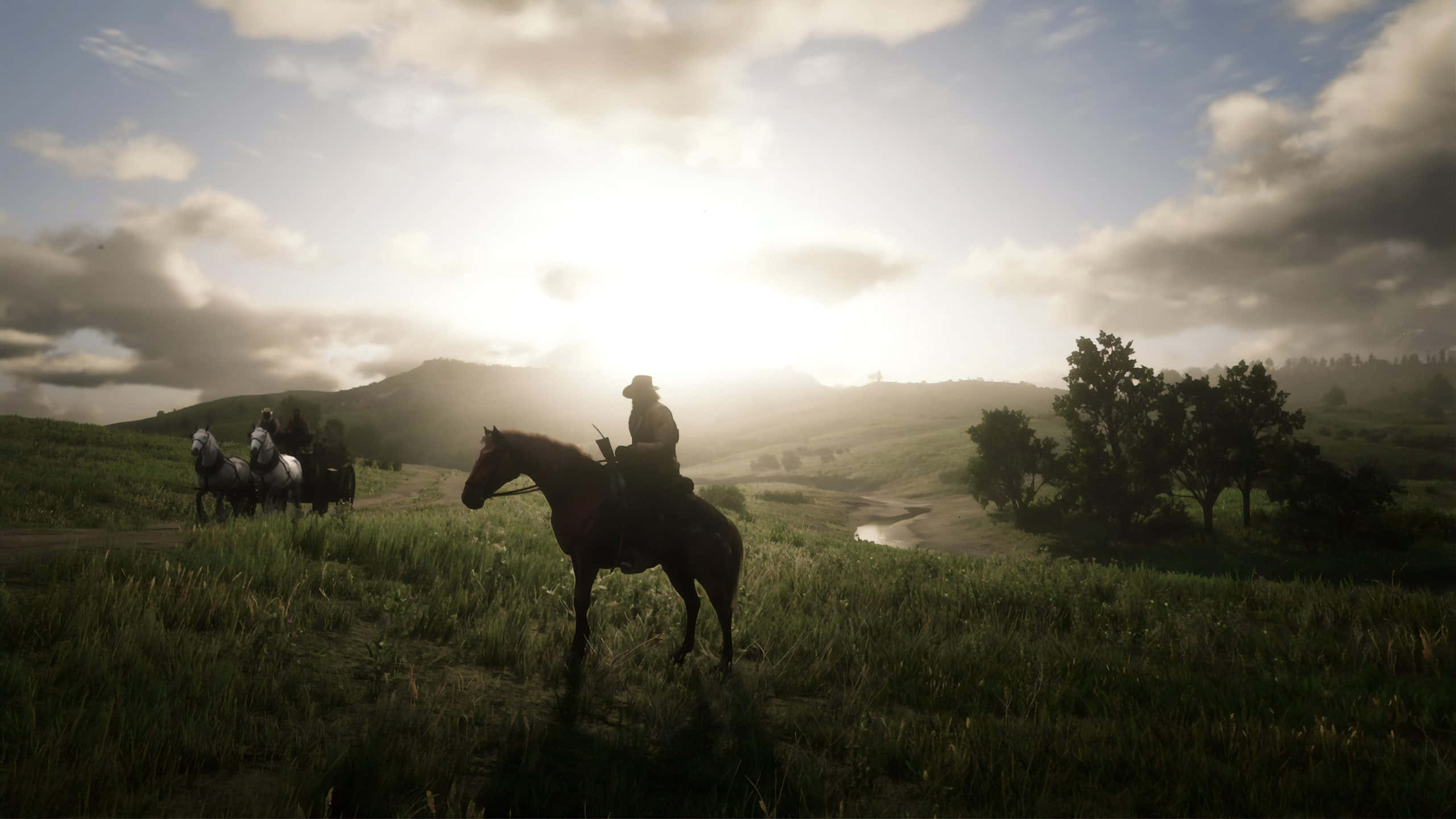 Red Dead Redemption 4K 桌布 壁紙 — 剪影的牛仔騎著馬穿過陽光照耀的草地山坡，遠處有山脈和散落的樹木，天空多雲。