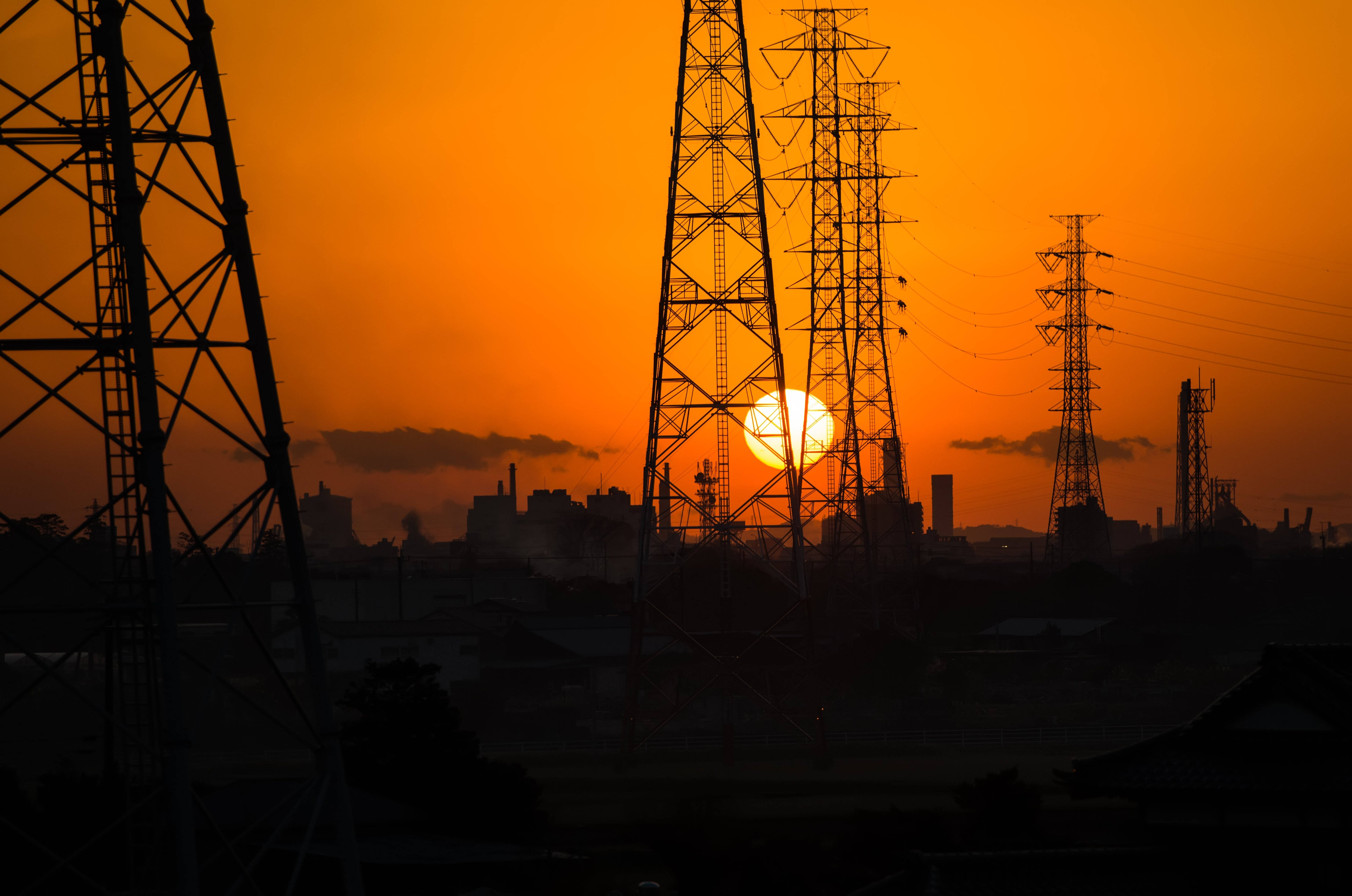 Sunset Aesthetic 桌布 壁紙 — 剪影的輸電塔勾勒出工業城市景觀上空閃耀的橙色日落。