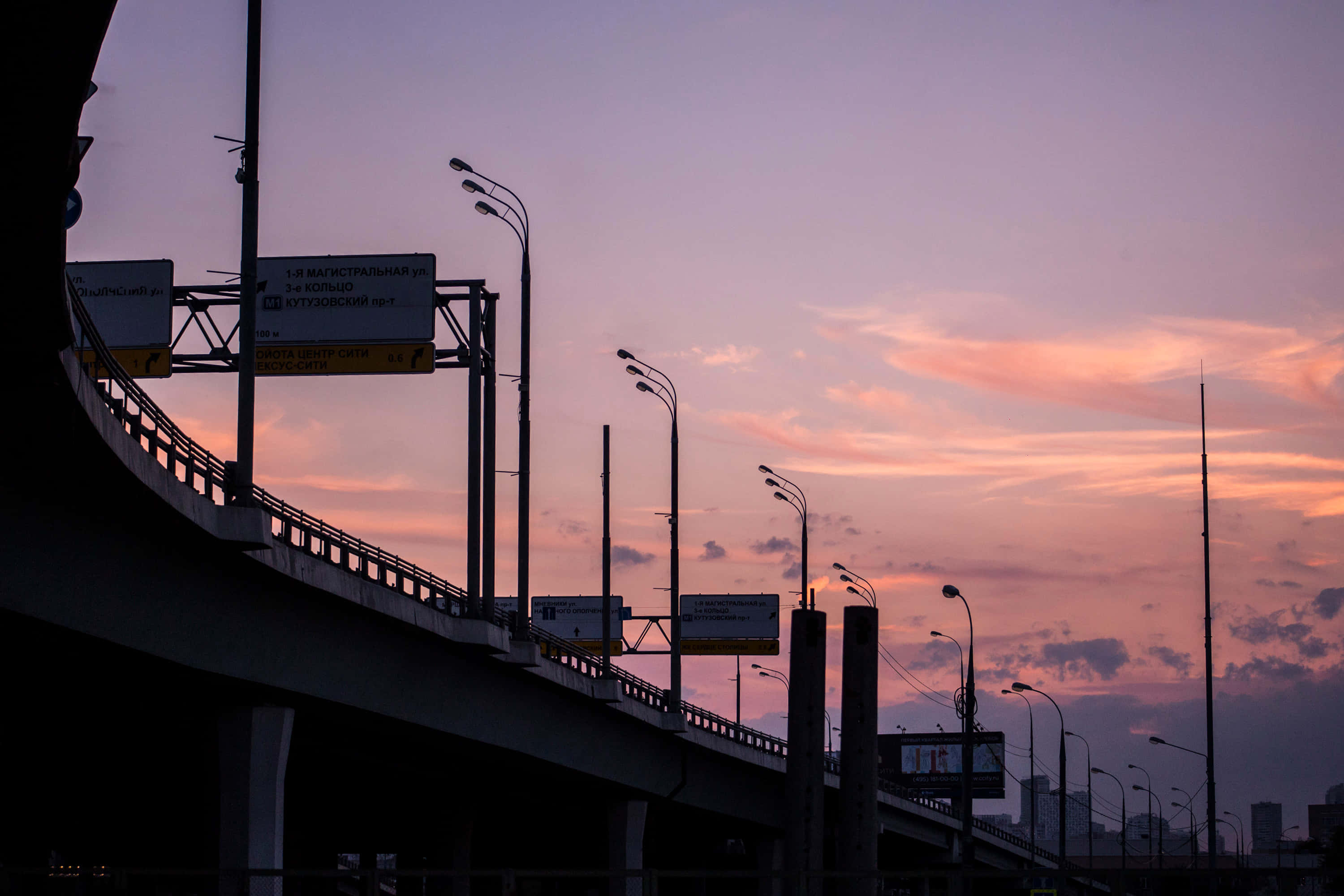 桌布 壁紙 — 剪影的高速公路高架橋在充滿活力的黃昏天空下延伸，天空染上粉紅、橙色和紫色。