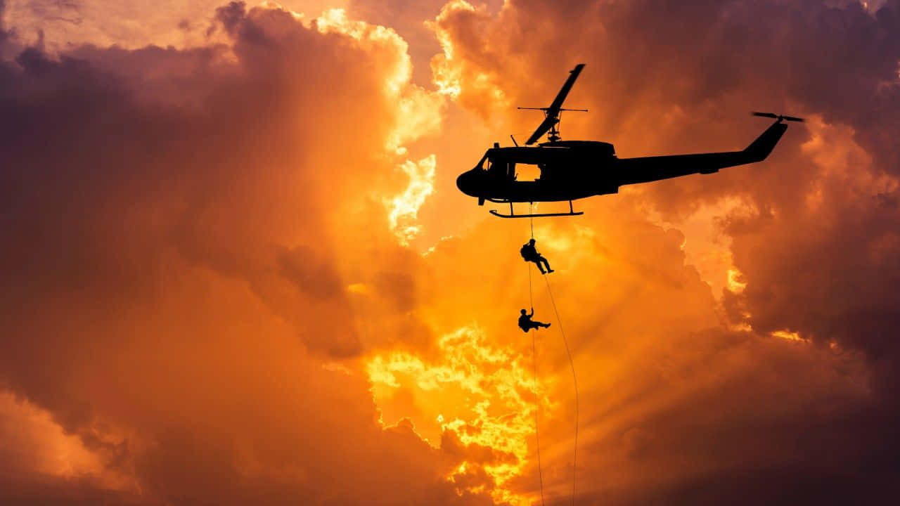 Helicopter 桌布 壁紙 — 剪影直升機在火紅的日落天空和戲劇性的雲層中救援兩個人。