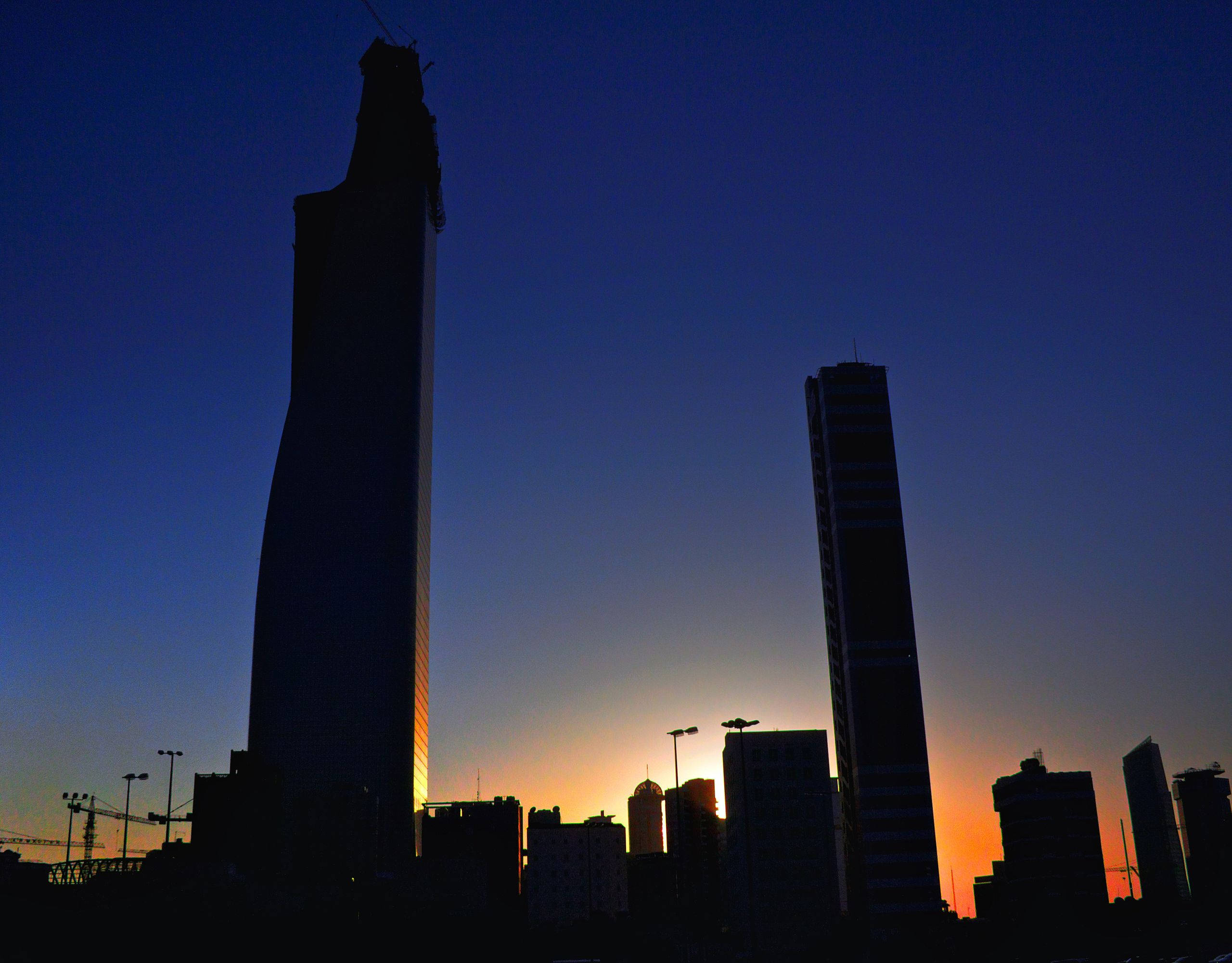Kuwait 桌布 壁紙 — 剪影般的摩天大樓在夕陽橙與深藍色調的漸變天空中升起。