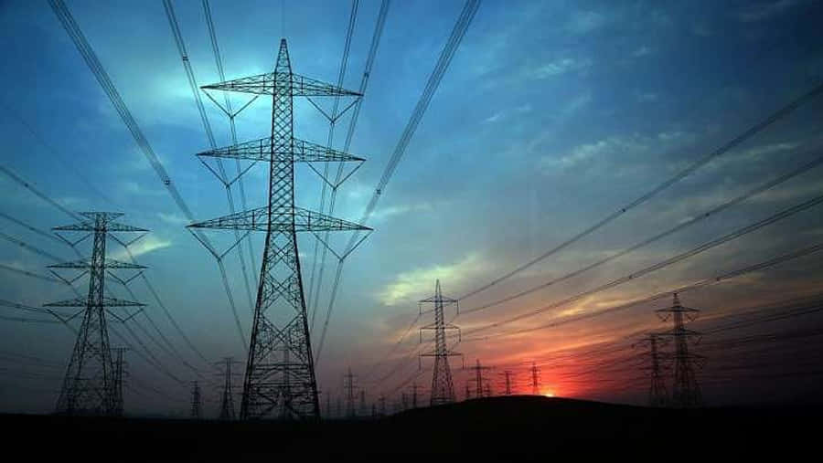 電力 桌布 壁紙 — 剪影般的輸電塔在暮色天空中延伸，天空被塗上火橙色和深藍色調。