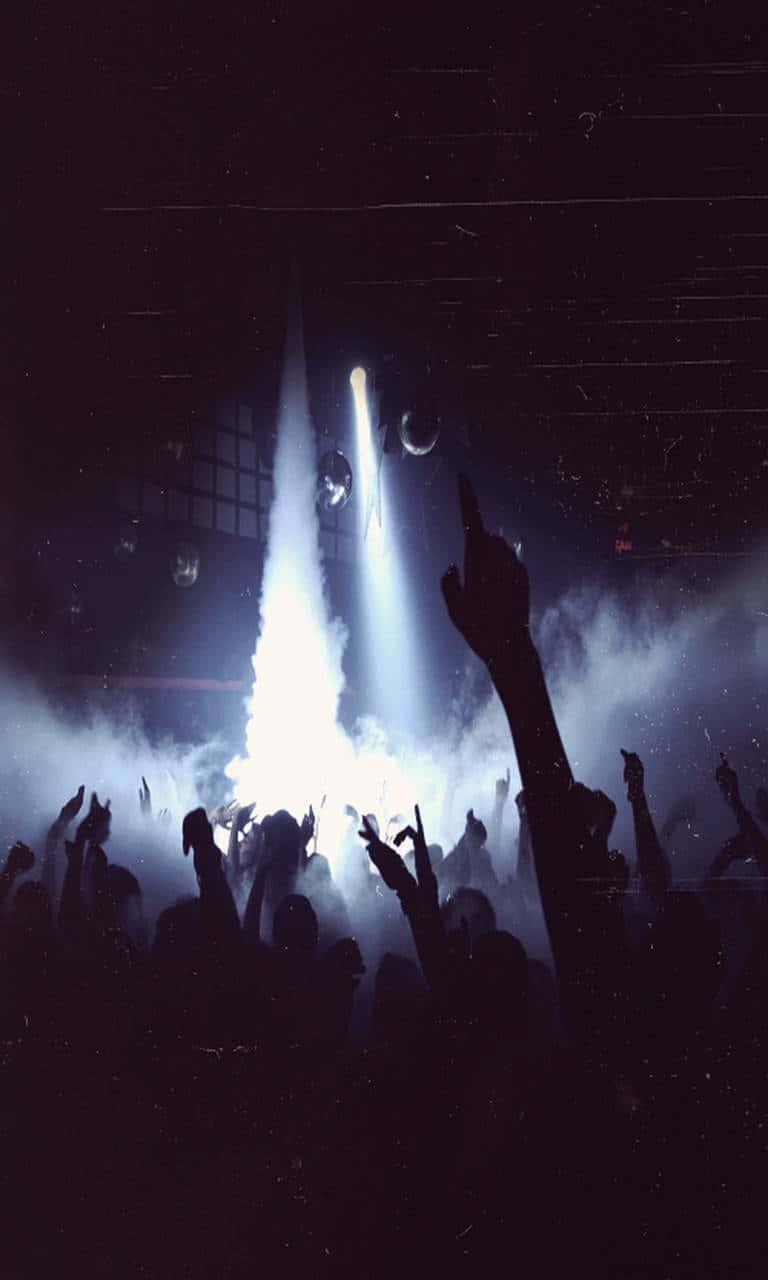 Club Party 桌布 壁紙 — 剪影般的音樂會人群在黑暗場地中，於一道穿過煙霧的明亮聚光燈下舉起雙手。